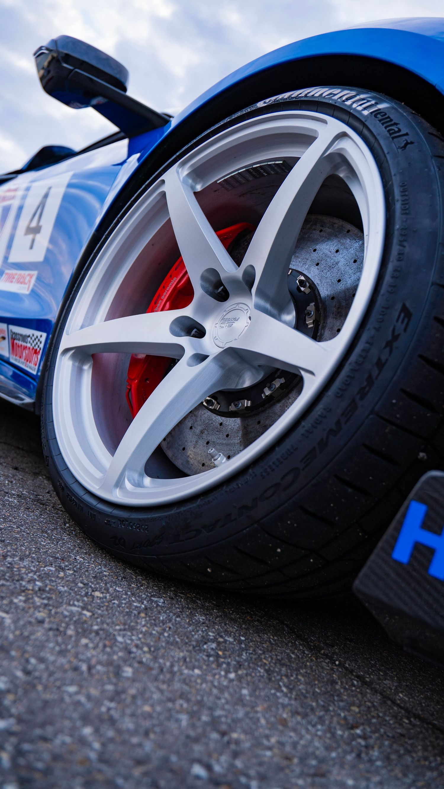Performance wheel detail showing white five-spoke rim and red brake caliper.