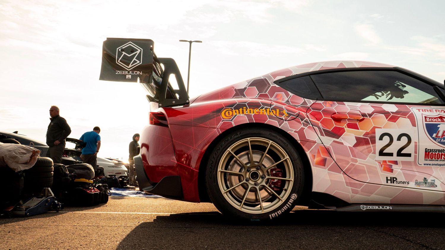 Side profile of pink race car with sponsor decals and custom wheels.
