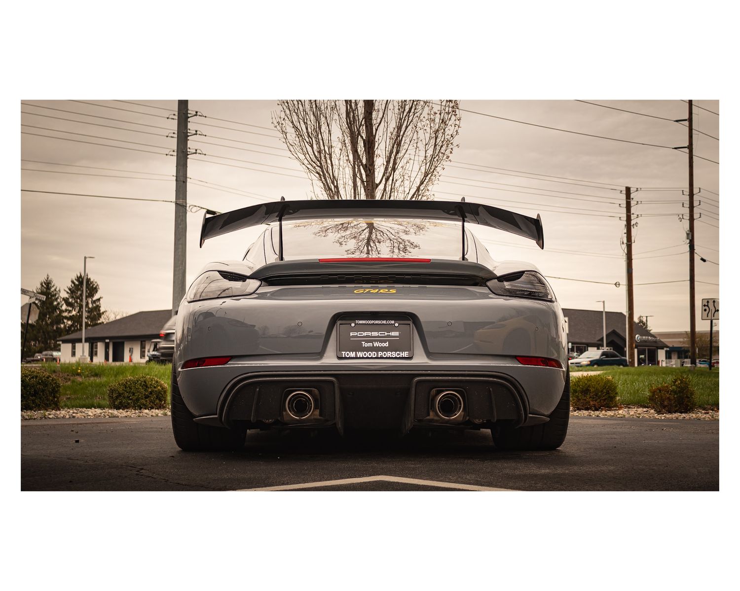 Rear view of a Porsche sports car with prominent dual exhaust and large rear wing.
