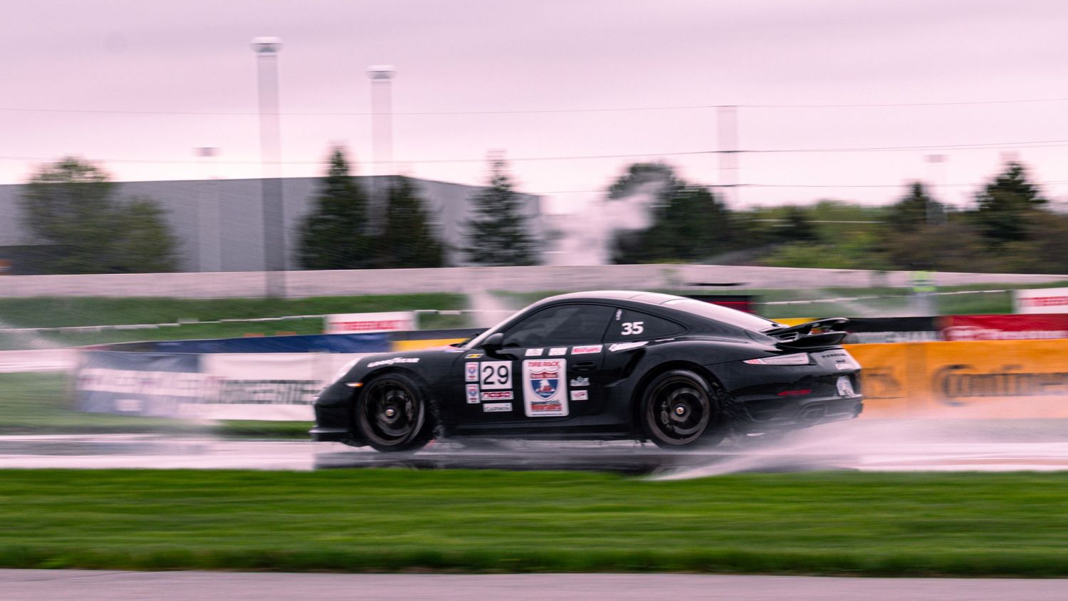 Black racing car creating spray while cornering at high speed.