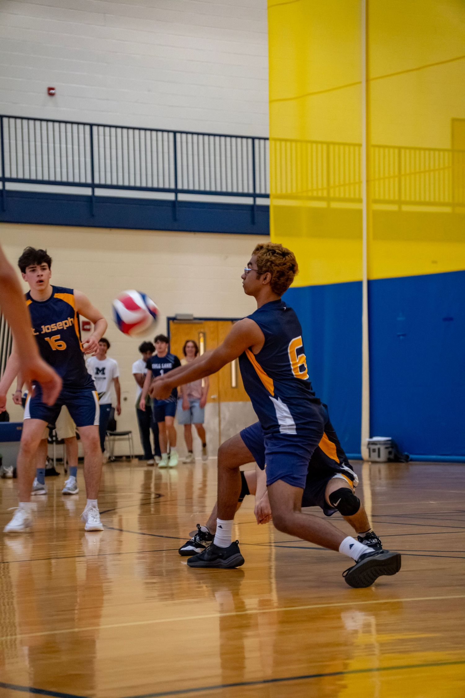 Player in navy uniform prepares to set the volleyball during an indoor match.