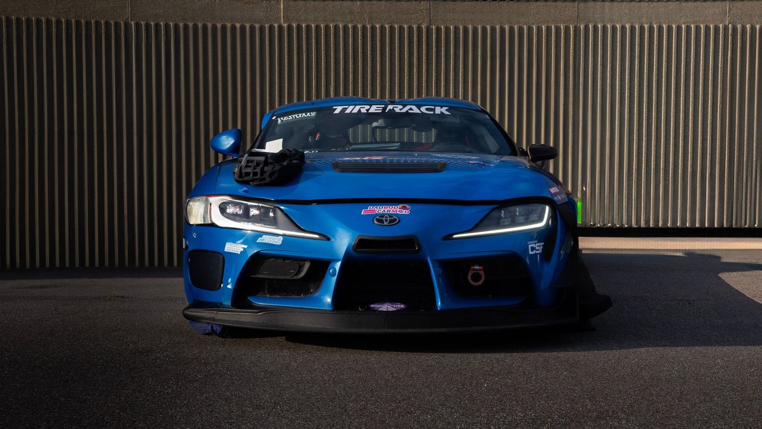 Front view of a modified blue Toyota Supra with custom LED headlights and aerodynamic bodywork.