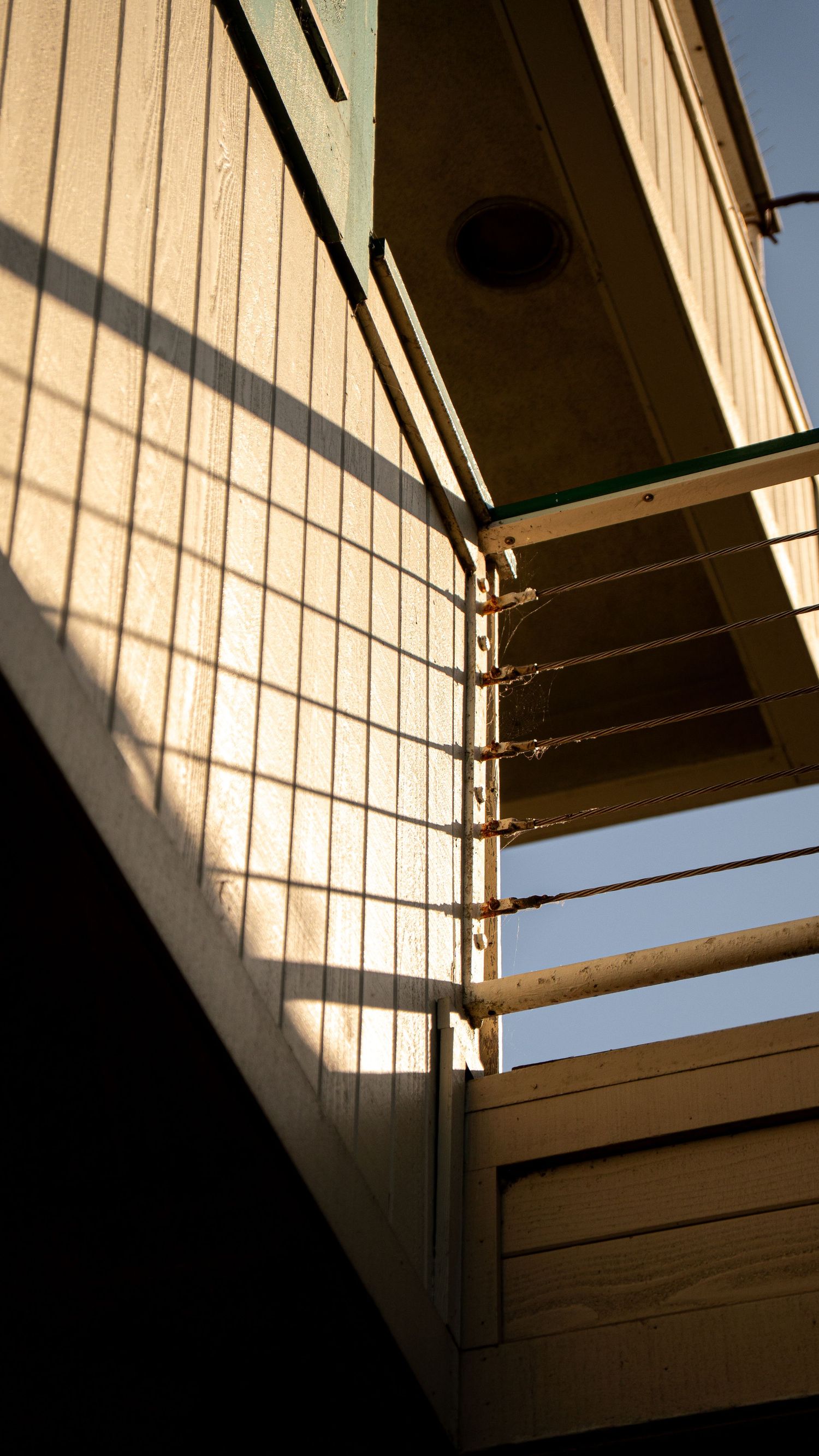 Geometric shadows and lines cast on a beige wall create an abstract architectural pattern.