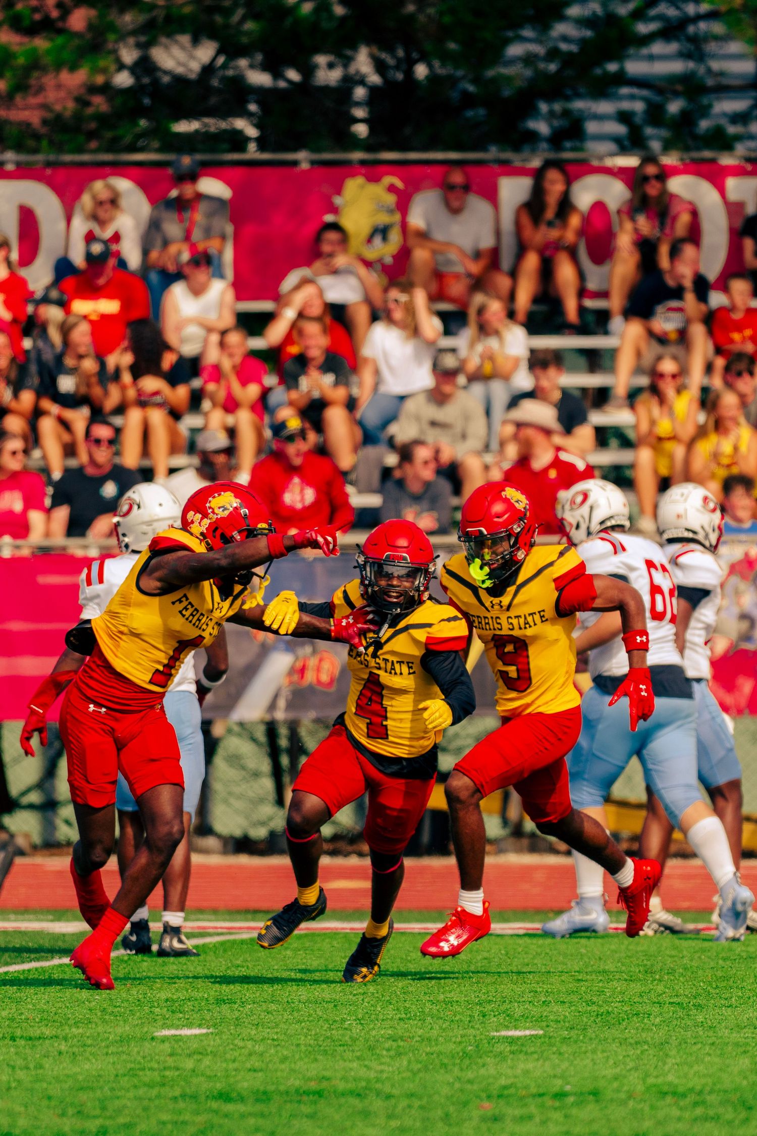 Football players in yellow and red uniforms crouch in formation on a grass field during a game.