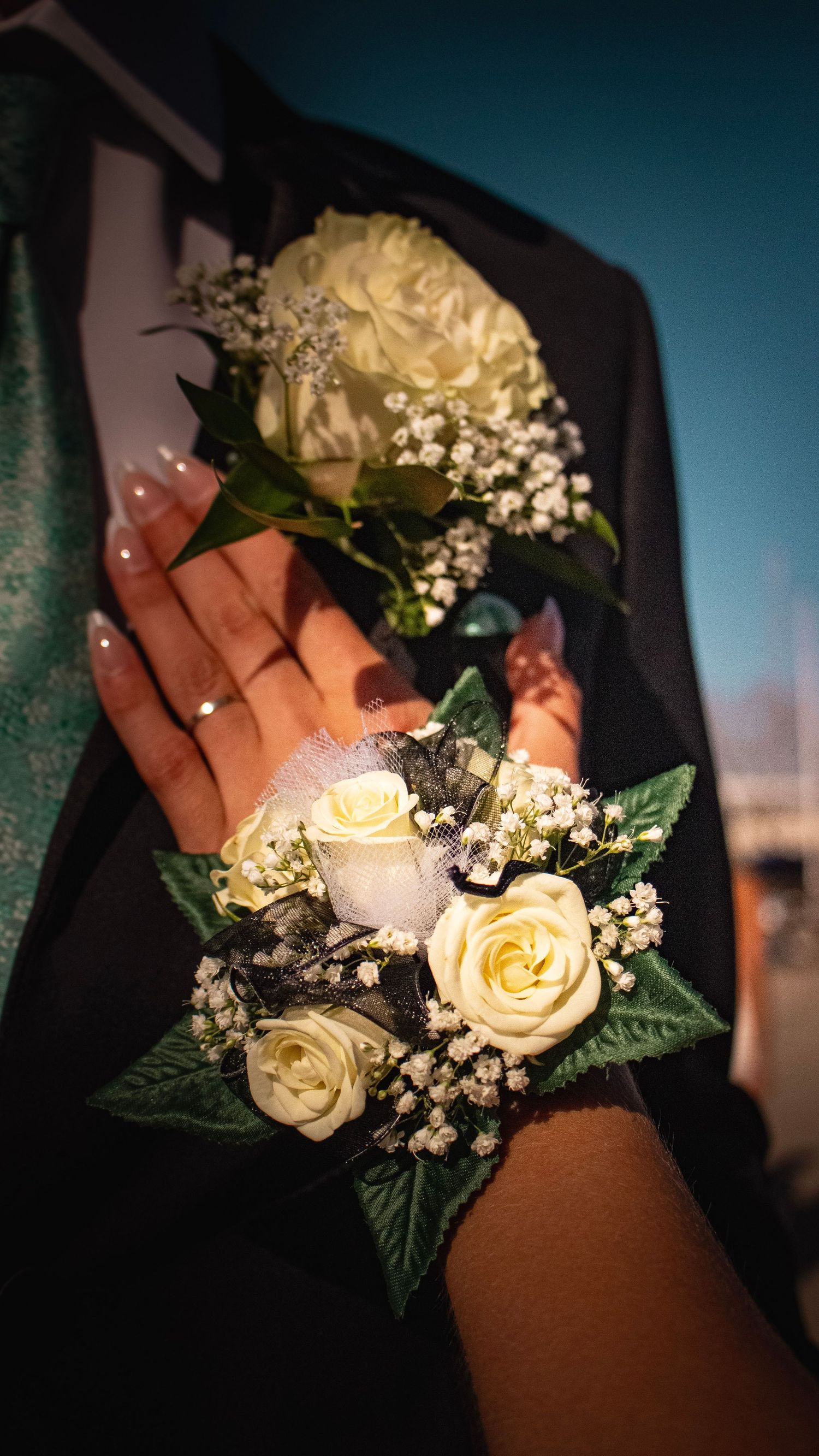 Close-up of cream roses and baby's breath corsages worn on formal attire.