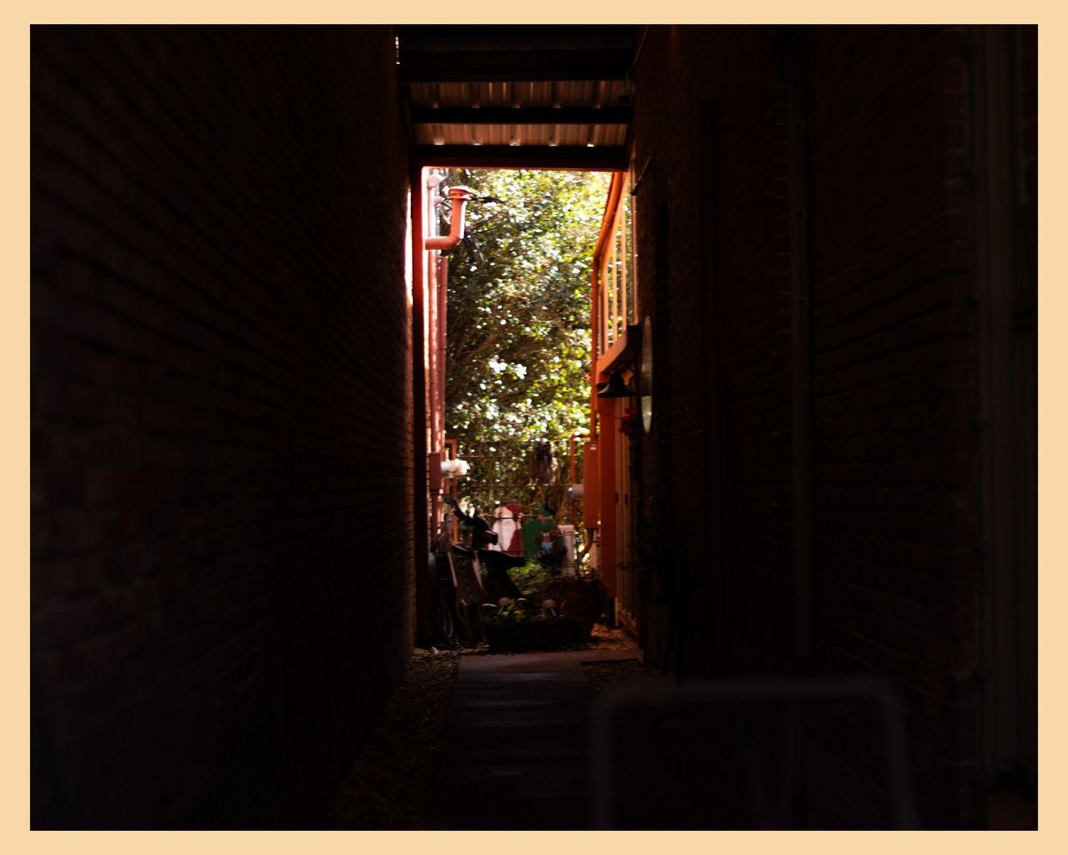 Dark doorway opening to reveal an illuminated garden with greenery and flowers.