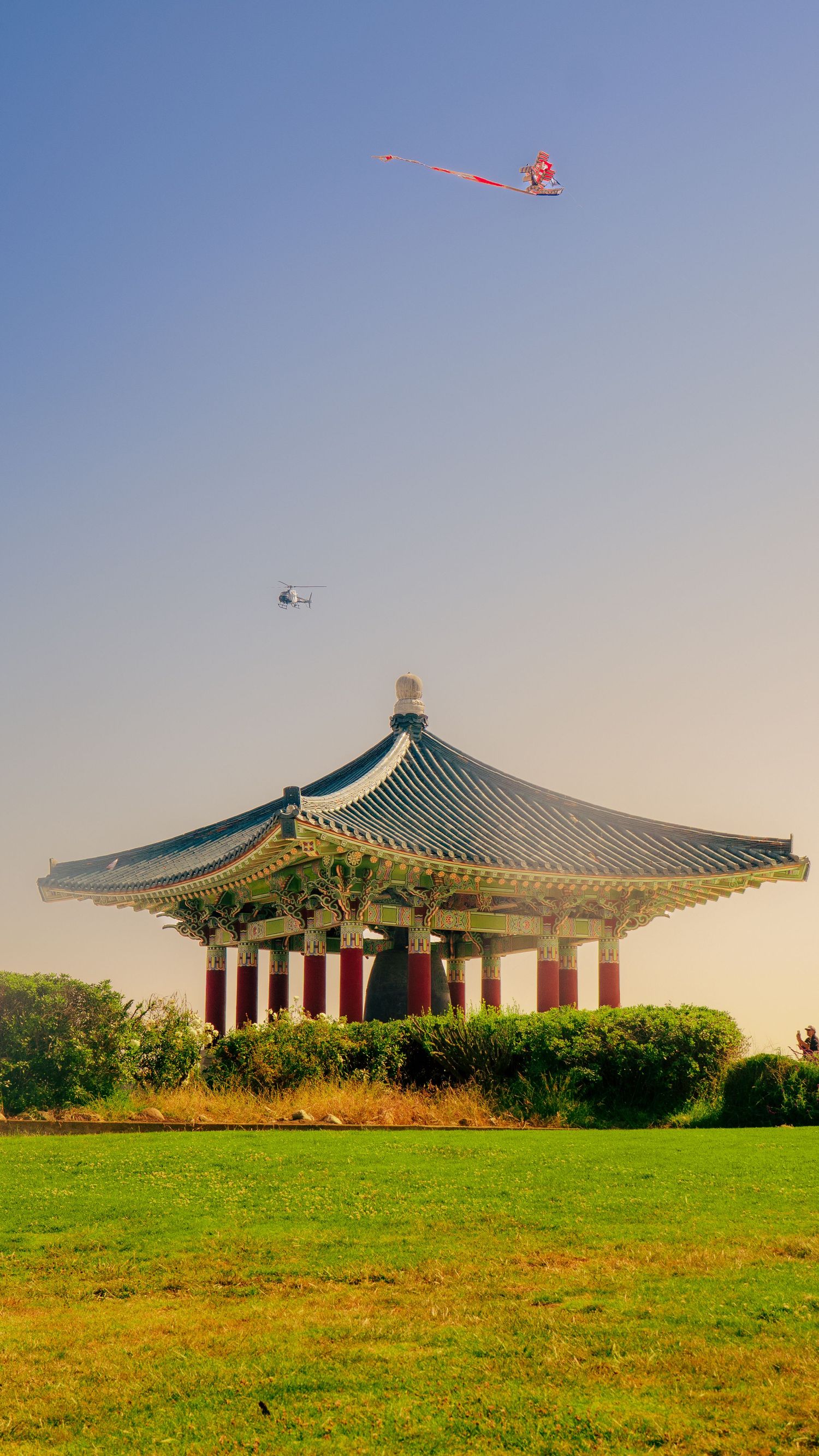Korean pagoda with red kite flying overhead in sunset sky.