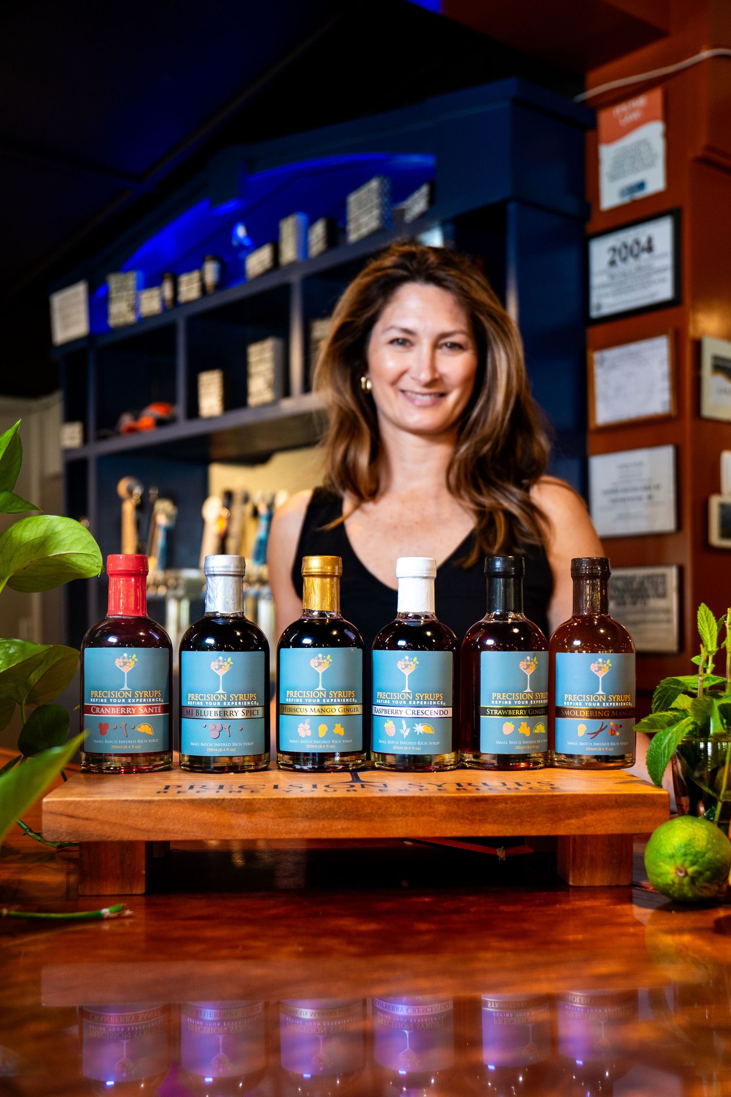 Artisanal spirits lineup displayed on polished wooden bar with ambient lighting and greenery.