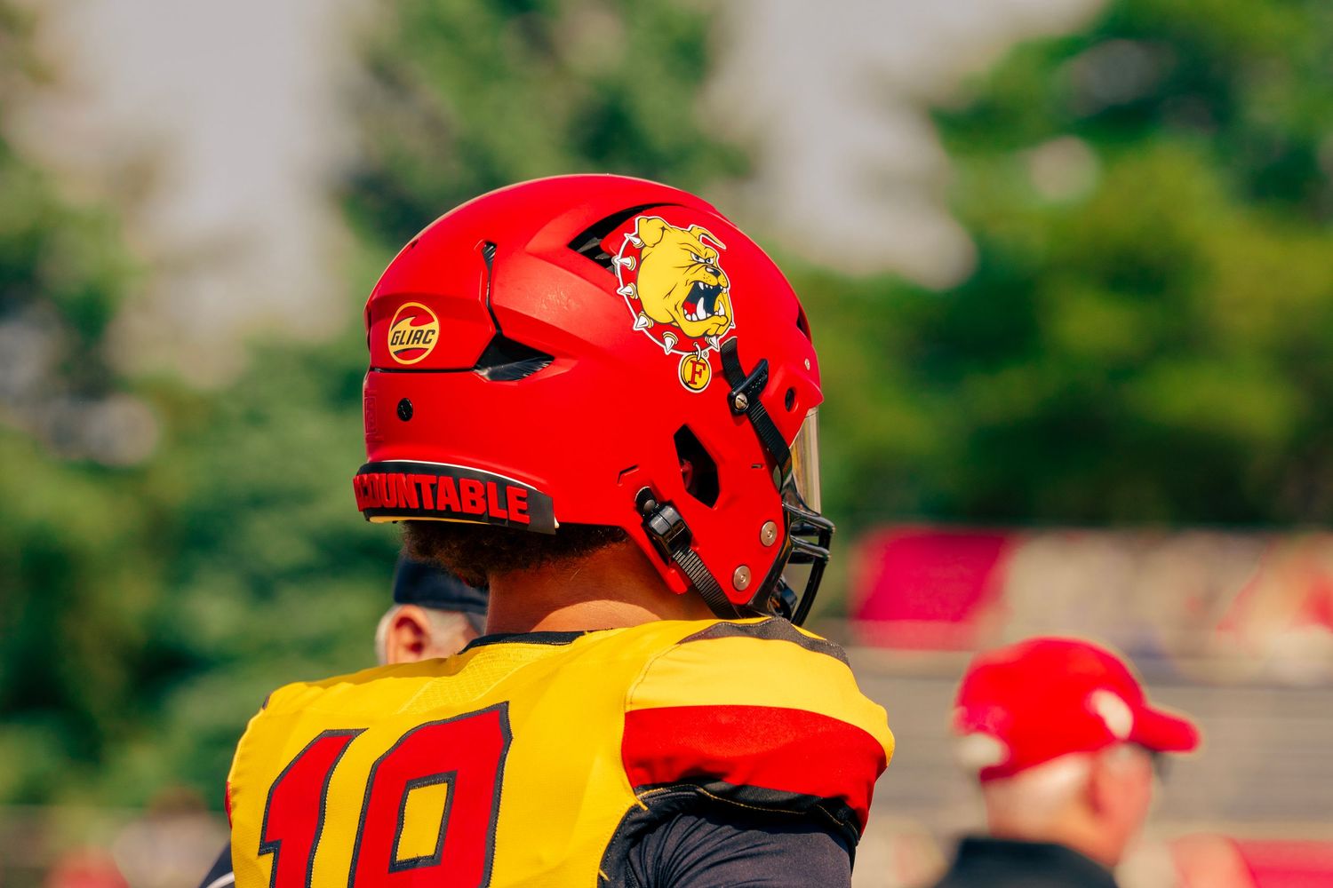 Football players in red and yellow uniforms huddle together during a game on the field.