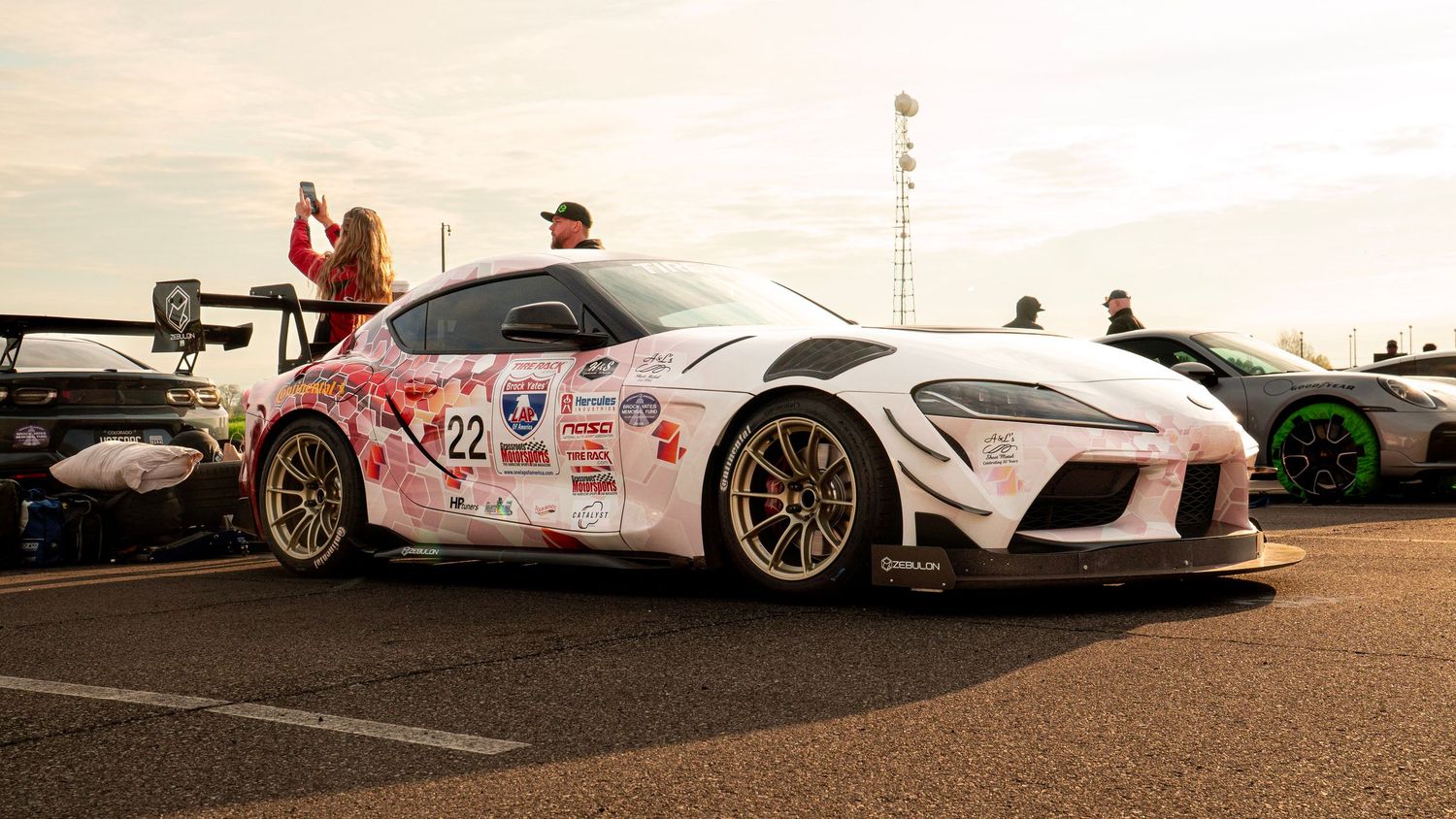 Modified Toyota Supra race car with custom white paint and racing decals parked on asphalt.