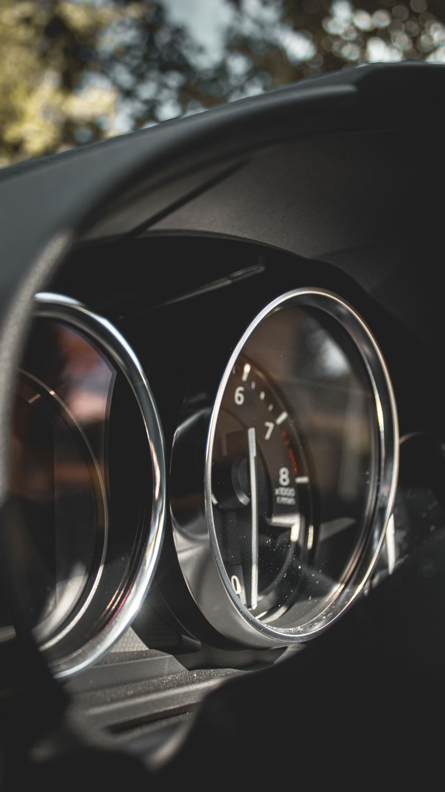 Close-up of modern car instrument cluster gauges with chrome trim rings.