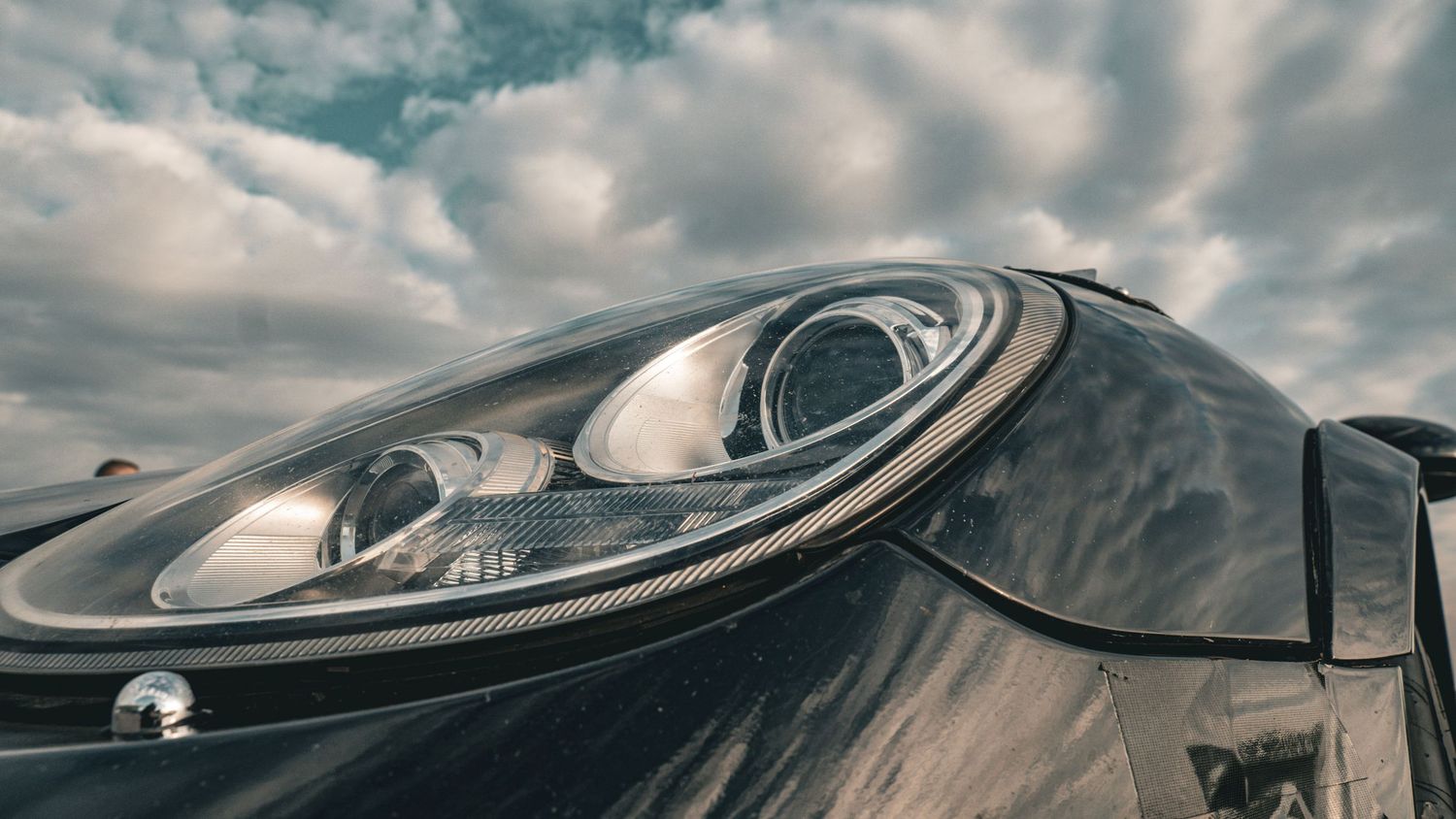 Close-up of sleek black sports car headlight with curved design details.