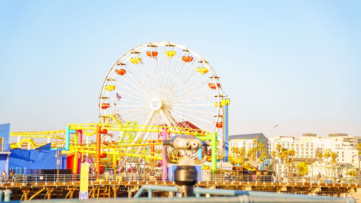 Panoramic view of a Ferris wheel and beachfront buildings along the coastline.