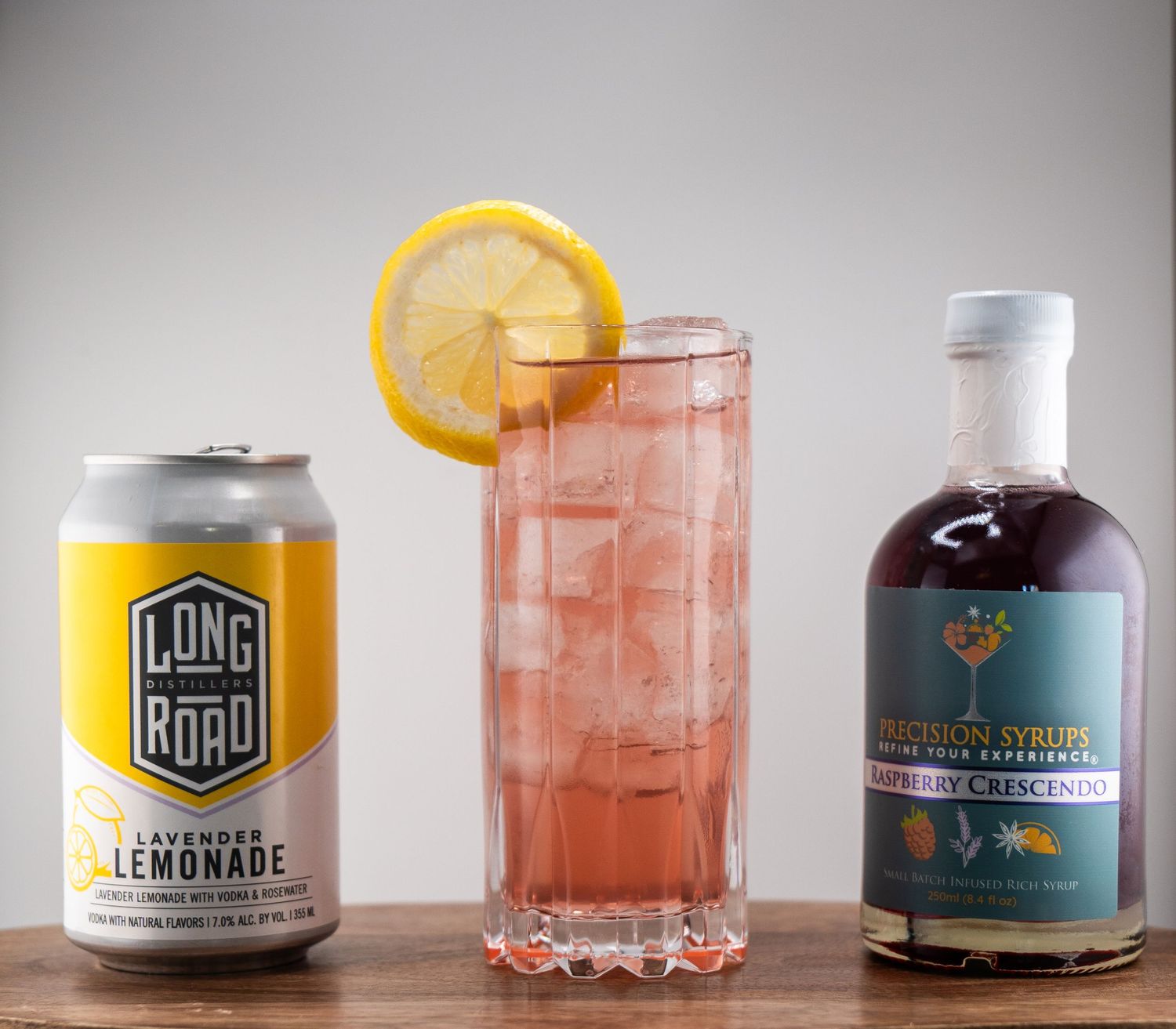 Craft cocktail with lemonade can and orange garnish served in a tall glass with ice.