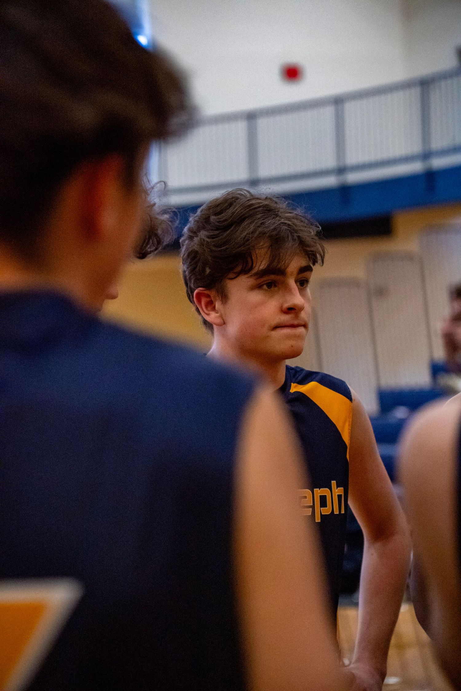 Team members in navy and gold uniforms watching intently from the sidelines.