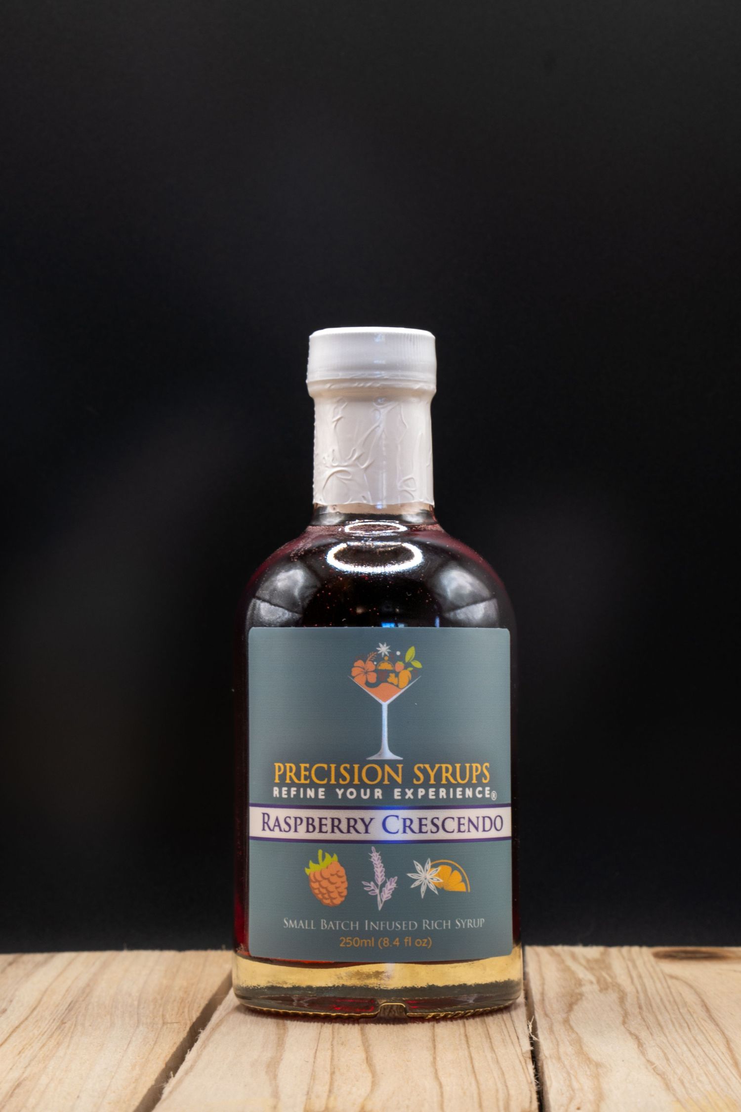 Precision Syrups MI Blueberry cocktail mixer bottle with white cap on wooden surface.