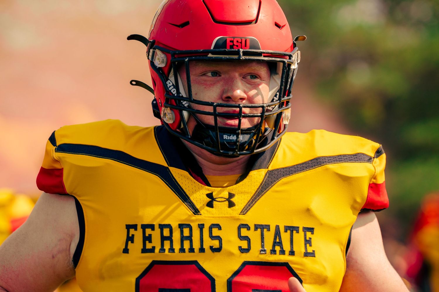 Football players in yellow Ferris State uniforms line up on the field during a game.