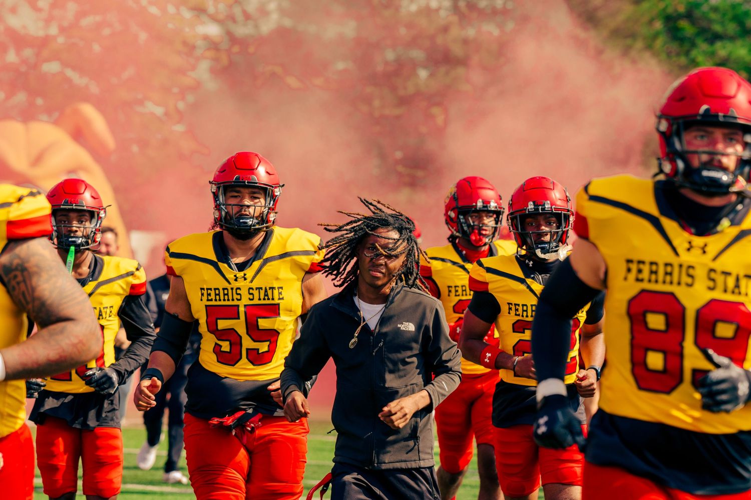 Football players in red and yellow uniforms line up in formation during a game or practice session.