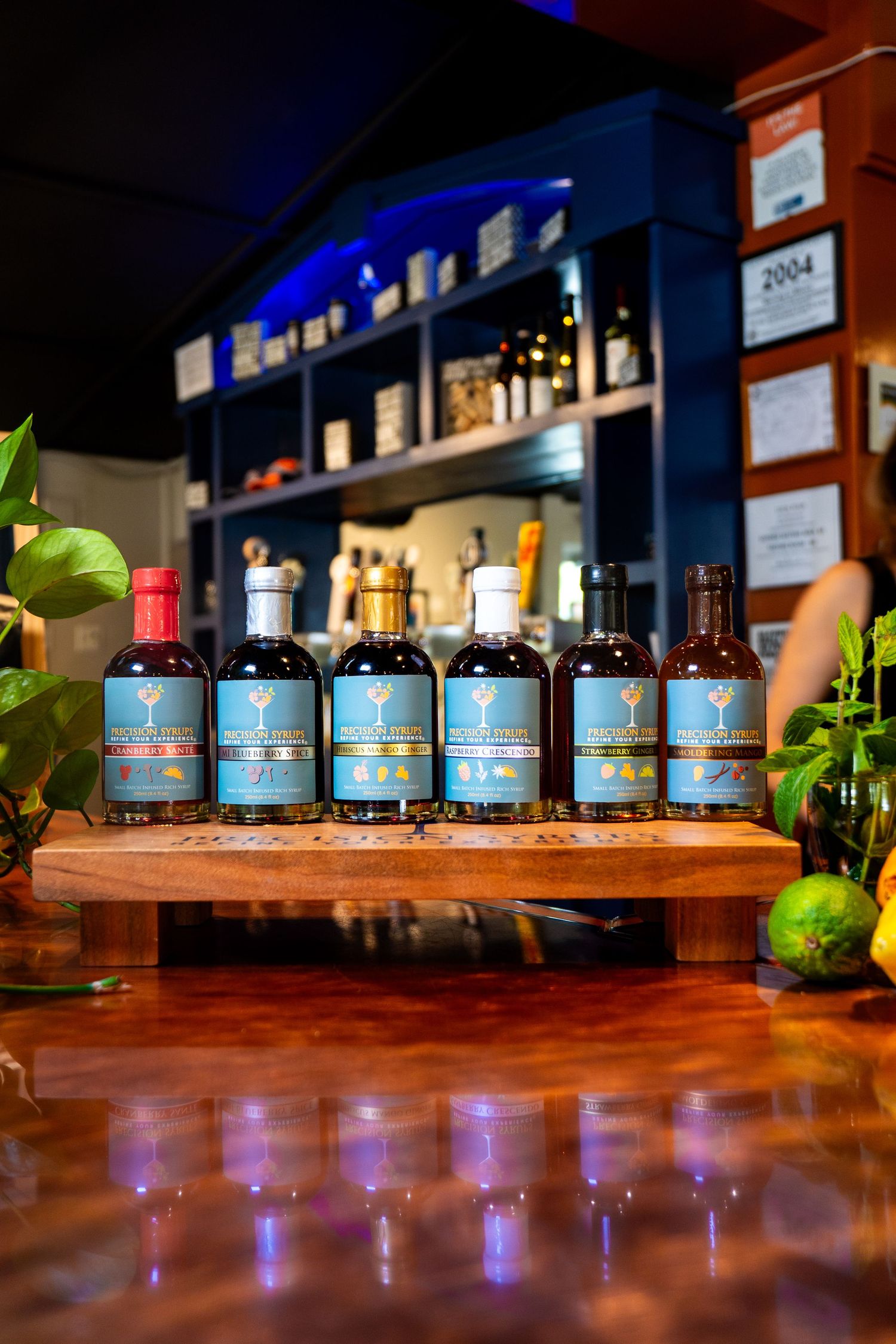 Collection of blue-labeled bottles arranged on wooden display shelf with atmospheric blue lighting.