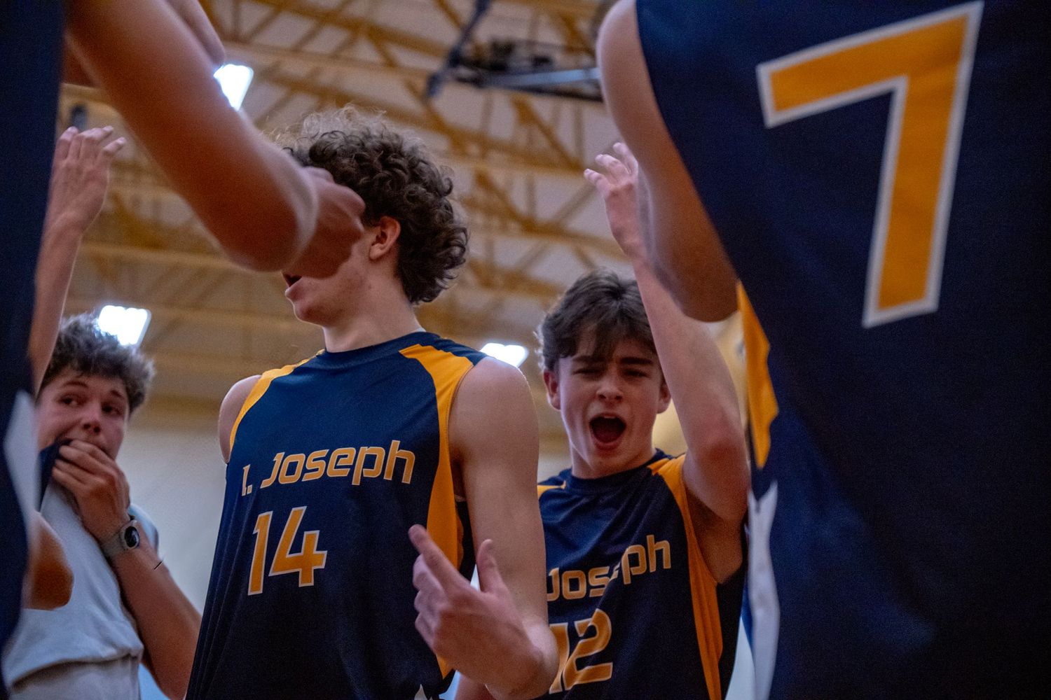 Volleyball team celebrating a point with raised arms and excited expressions.