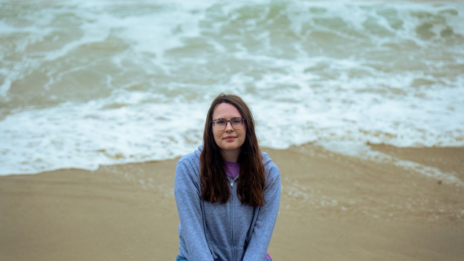 Waves roll onto a sandy beach under an overcast sky creating a serene coastal scene.