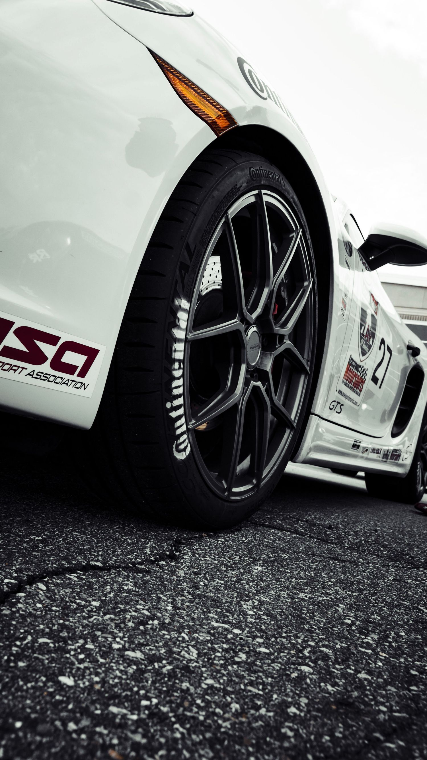 Close-up of white racing car wheel with Continental tire and black alloy rim.
