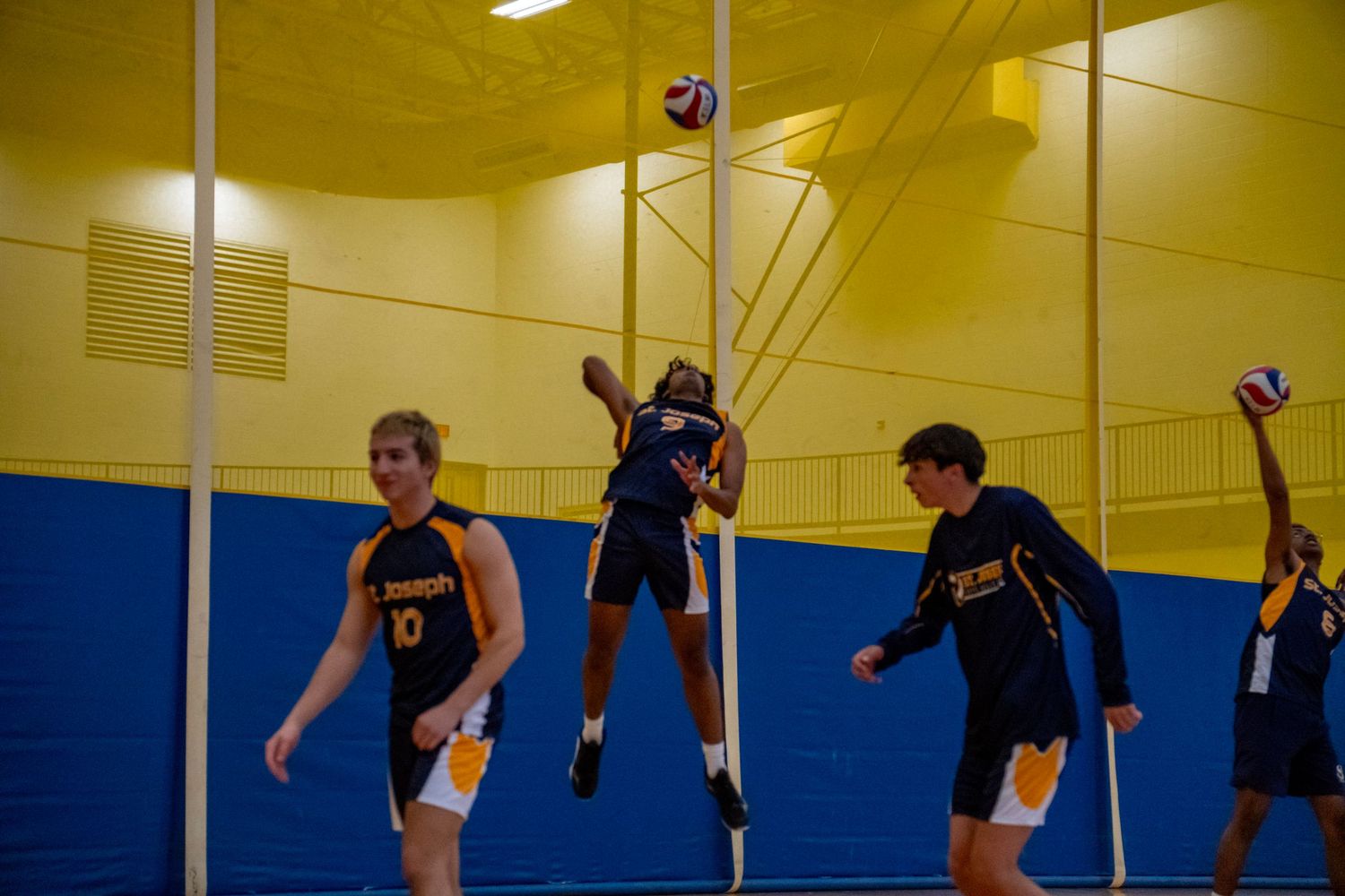 Players compete at the net during a high-stakes volleyball jump play.