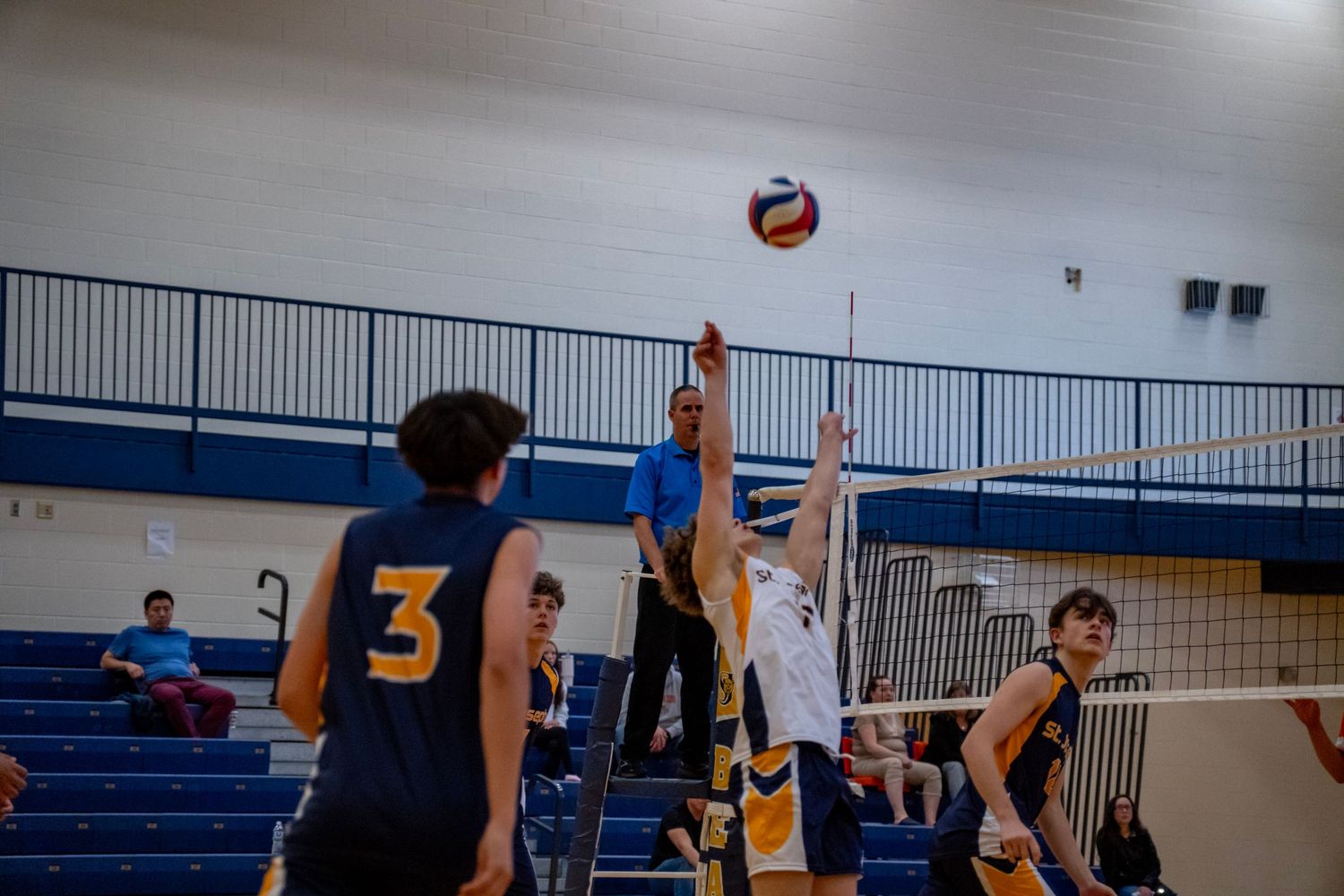 Multiple players positioned near the net ready to react during a volleyball rally.