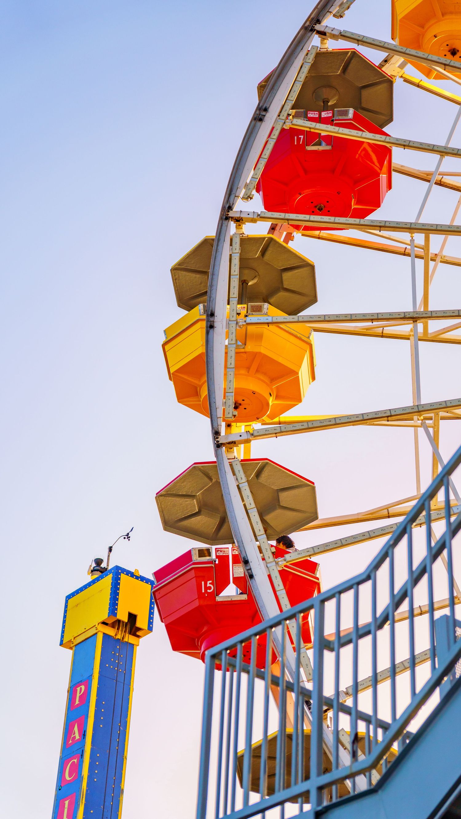 Colorful gondolas on Pacific Park Ferris wheel against bright blue sky.