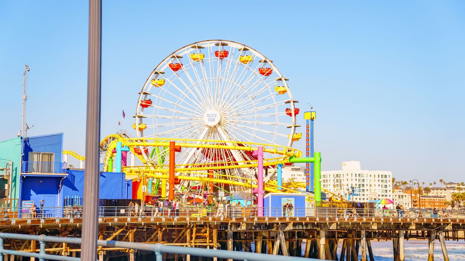 Santa Monica Pier's Pacific Wheel and amusement rides viewed from the boardwalk at sunset.