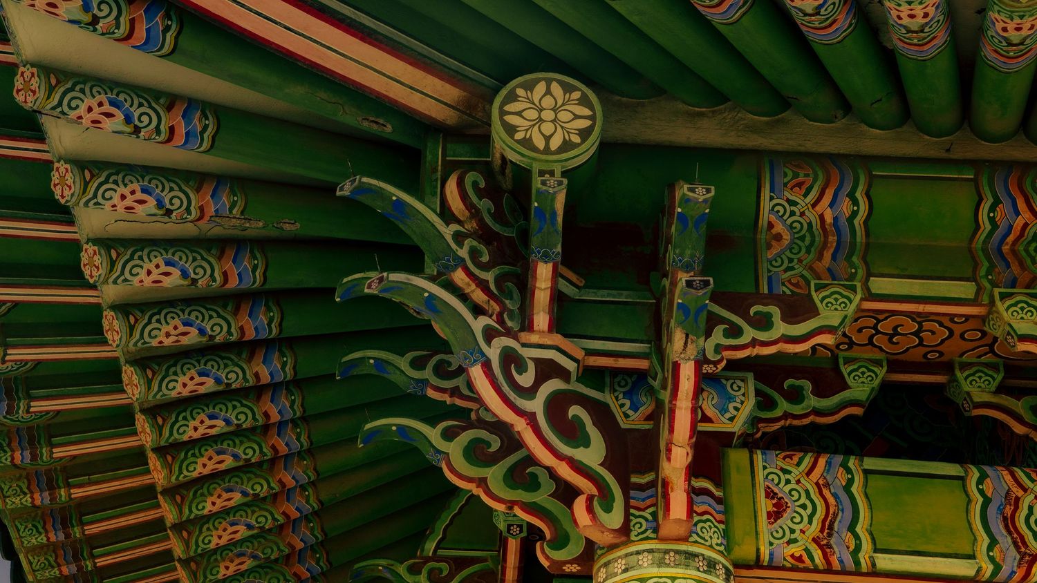 Detailed view of ornately painted wooden beams and decorative patterns on a traditional Korean temple ceiling.