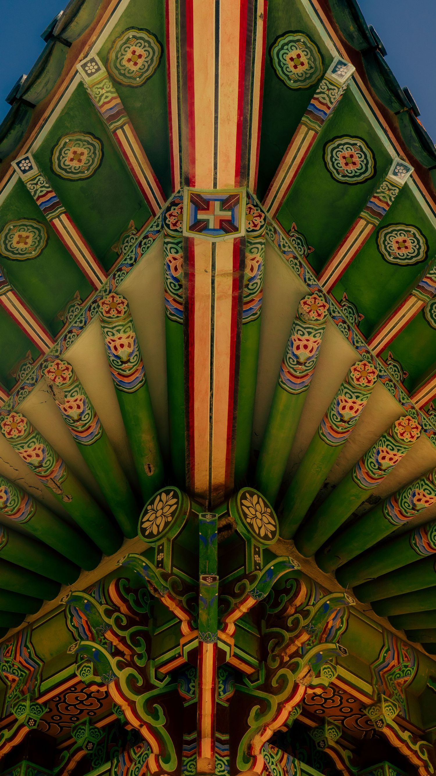Intricate geometric patterns and floral designs on traditional Korean temple ceiling in green and gold.