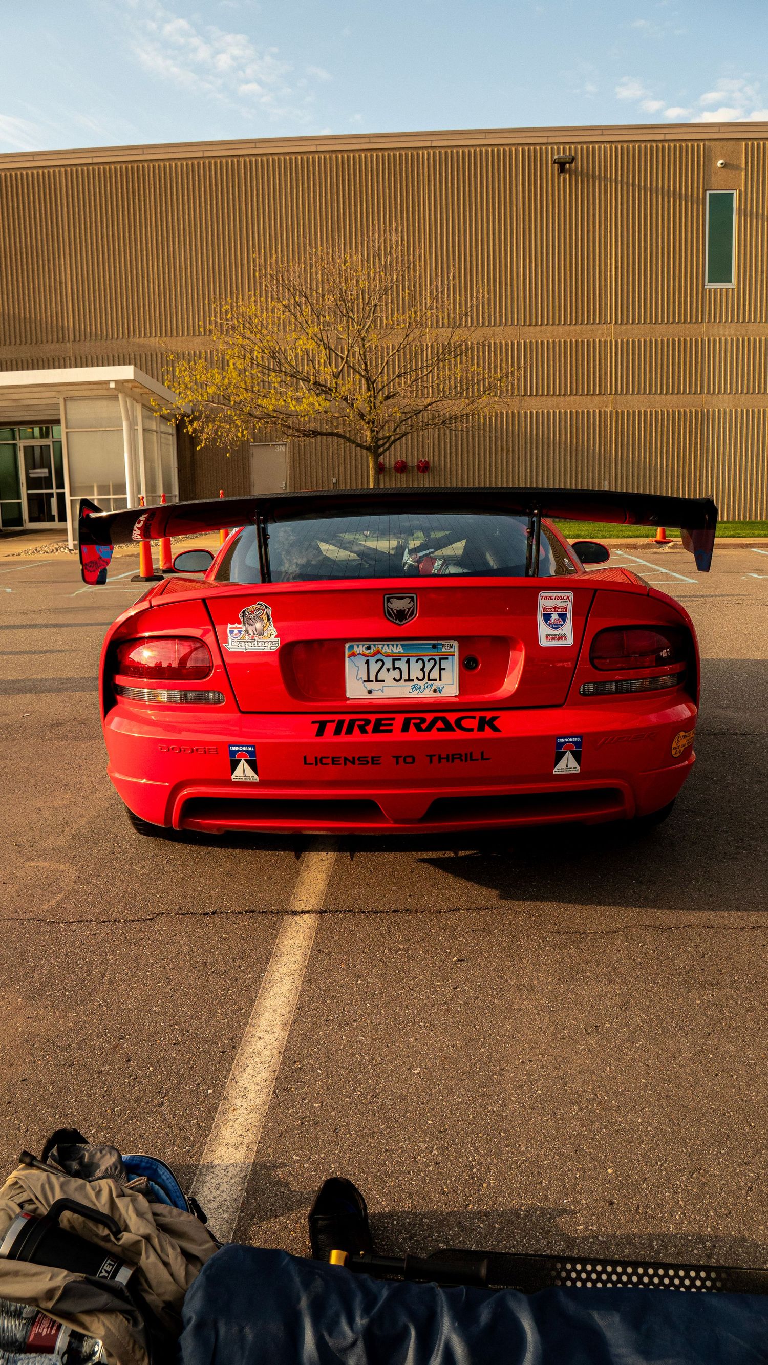 Rear view of red Dodge Viper with Tire Rack branding parked in front of commercial building.