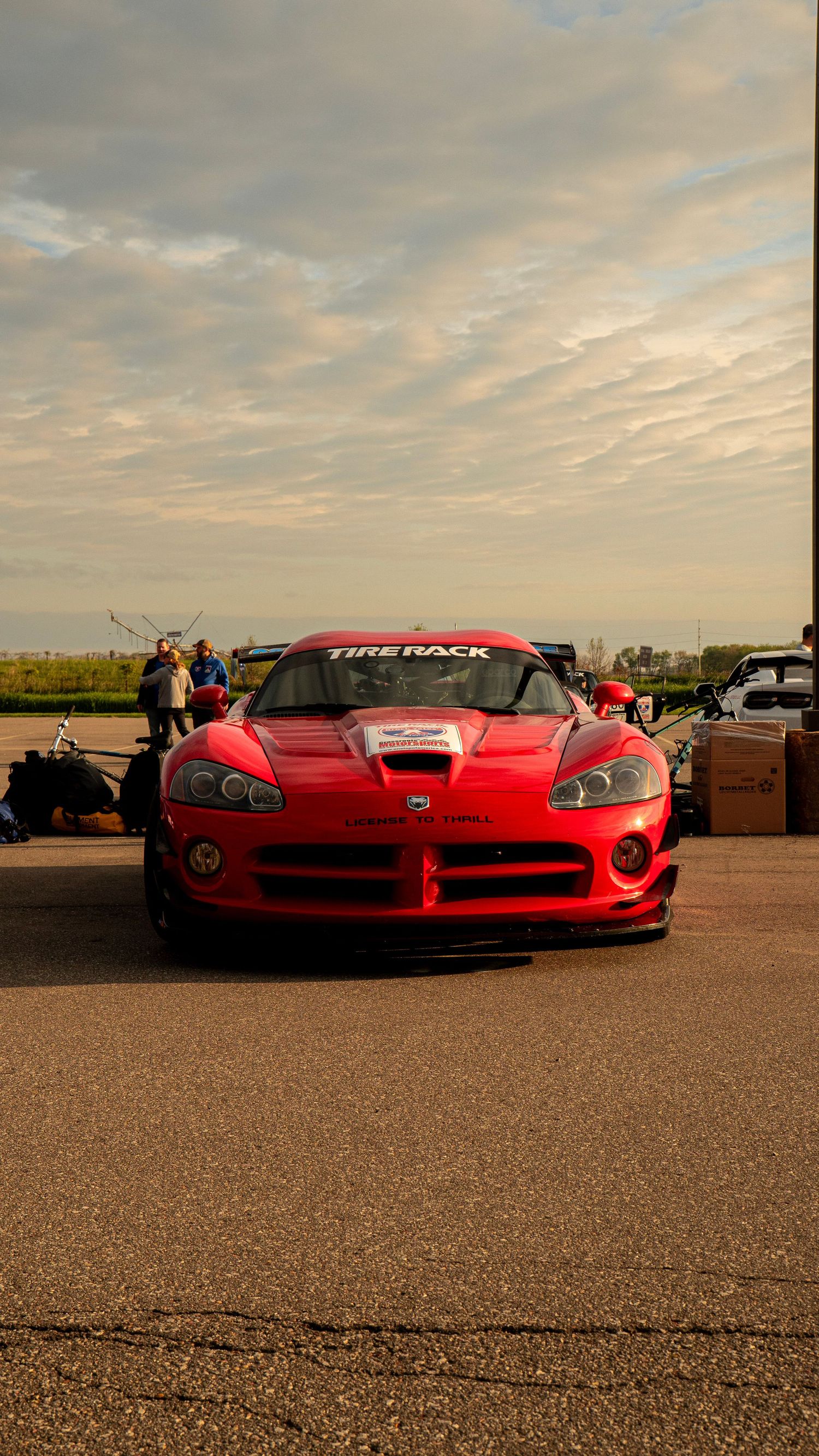 Red Dodge Viper sports car with Tirehawk branding parked under a dramatic sunset sky.