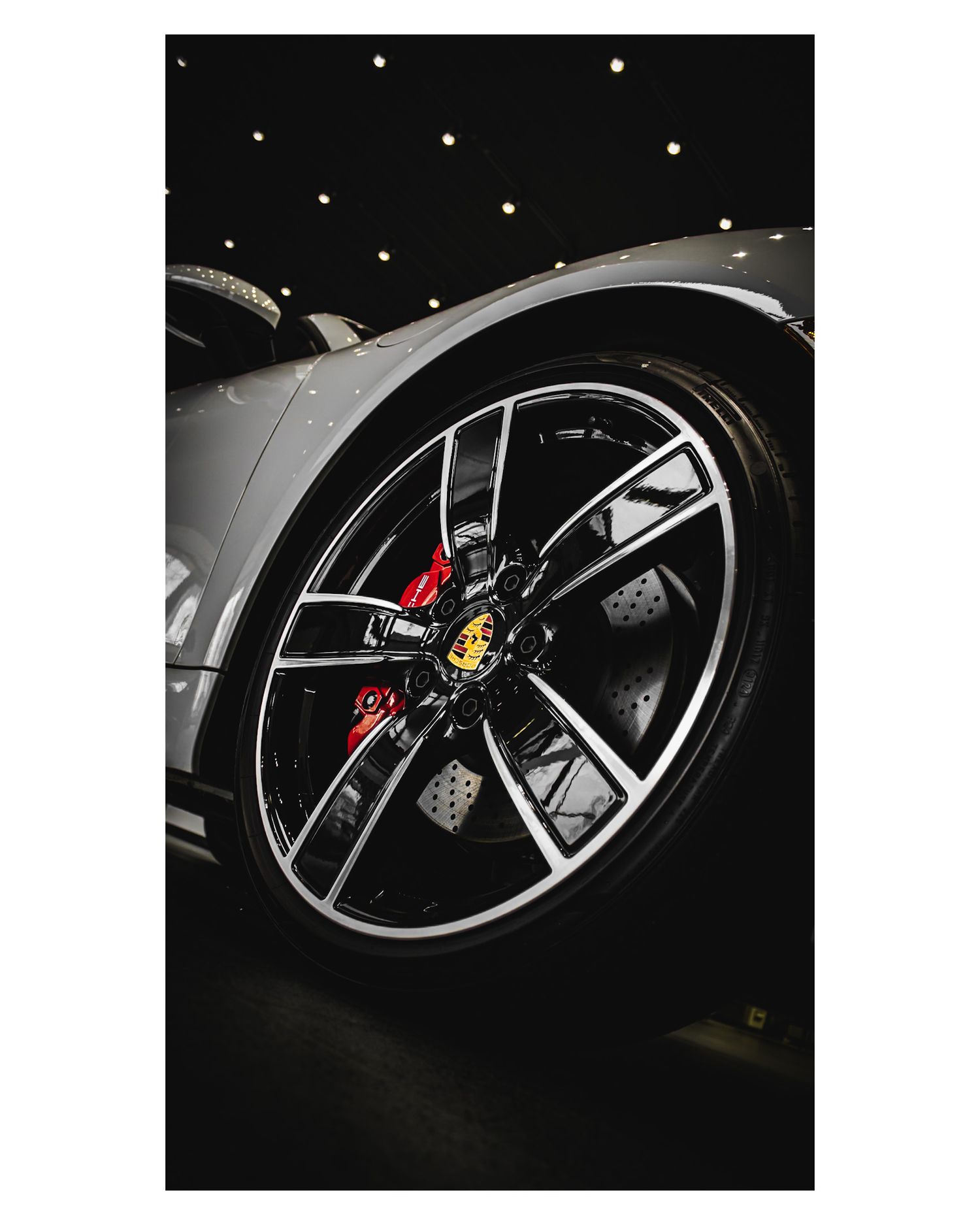 Close-up of a Porsche wheel featuring black alloy rim and red brake caliper.