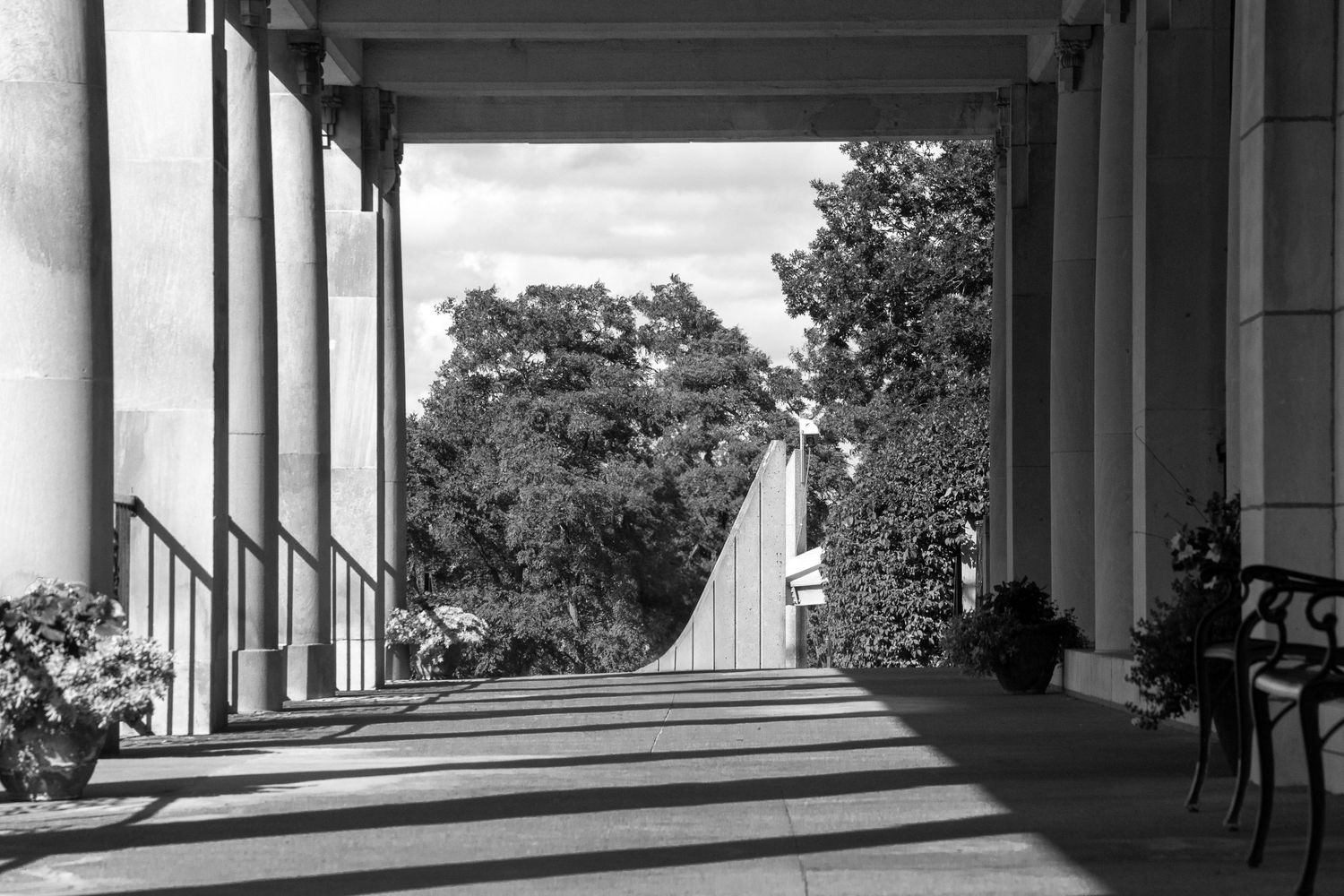 Black and white photograph of a colonnade with dramatic shadows cast through pillars.
