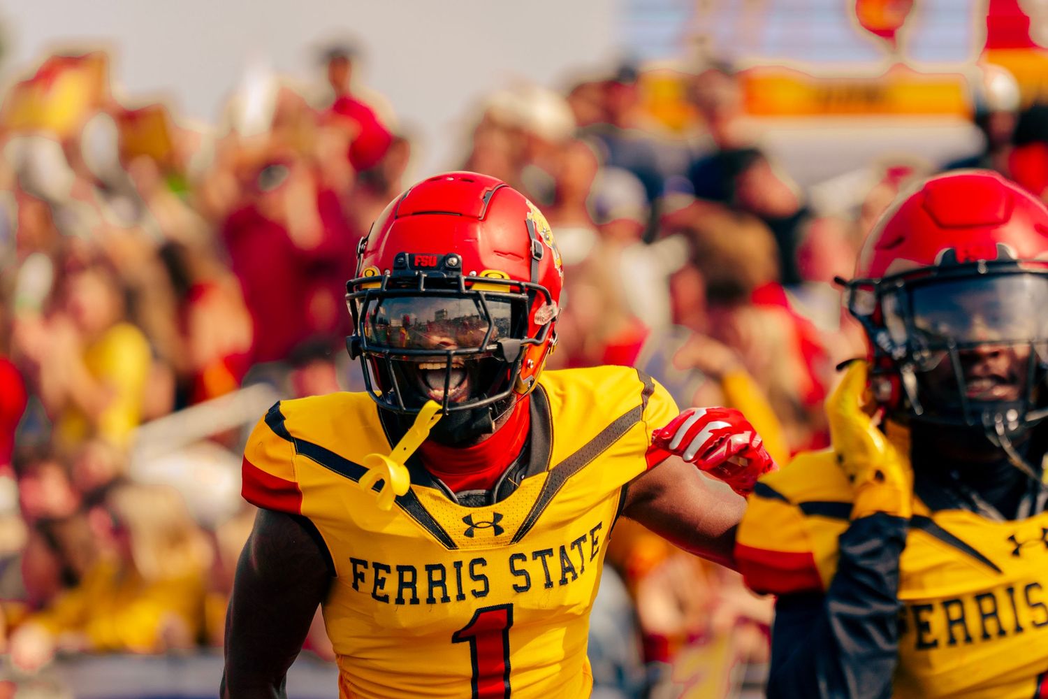 College football players in red and yellow uniforms clash during an intense game on the field.