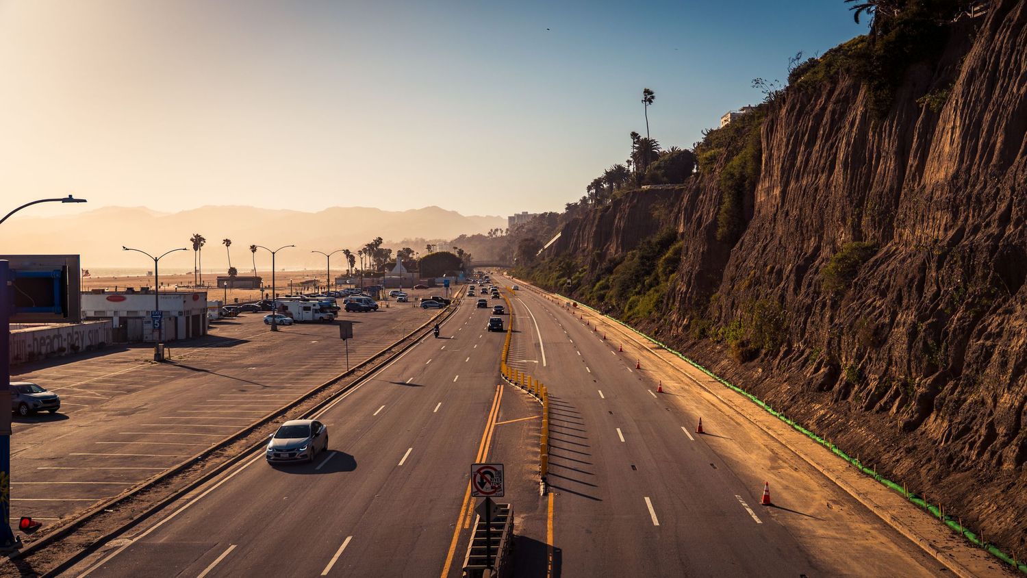 Scenic coastal highway curves alongside rocky cliffs and ocean views.