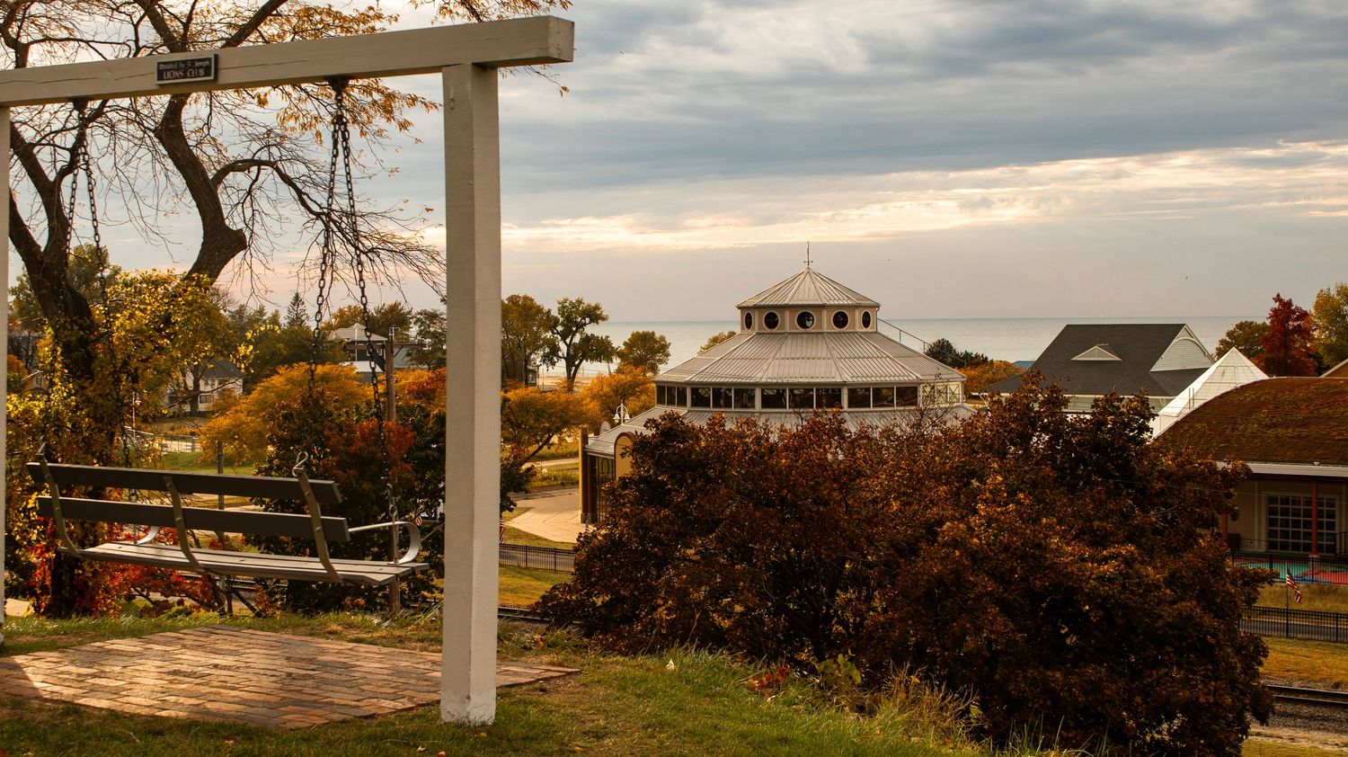 Panoramic coastal landscape with white pillars and autumn foliage under cloudy sky.
