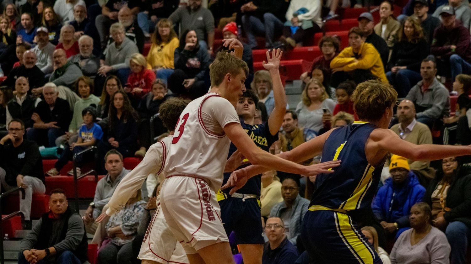 Basketball players from opposing teams reach for loose ball during intense game action.
