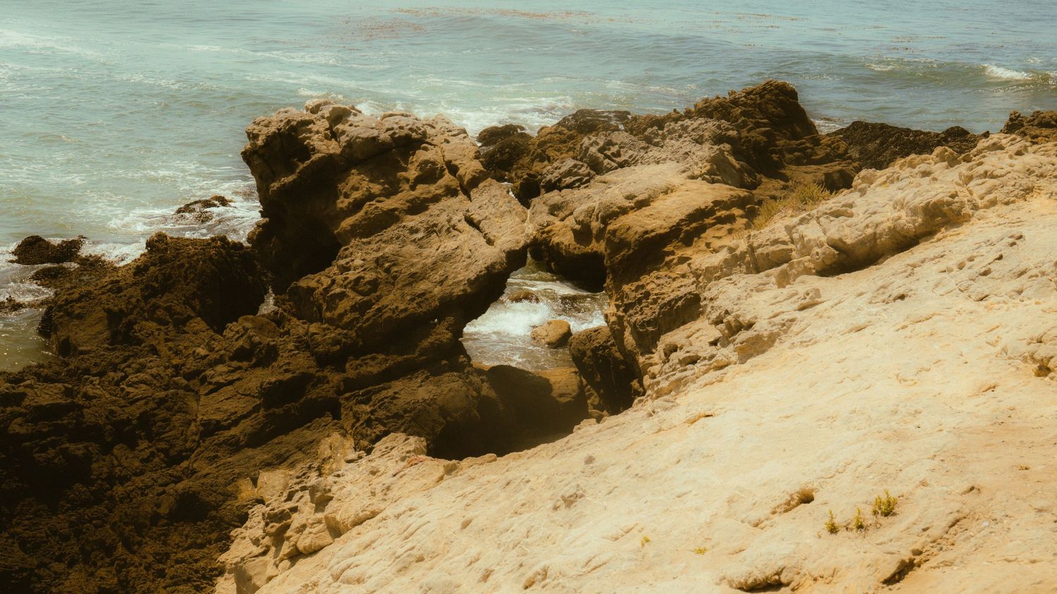 Rugged sandy cliffs along a dramatic coastal shoreline with crashing waves.