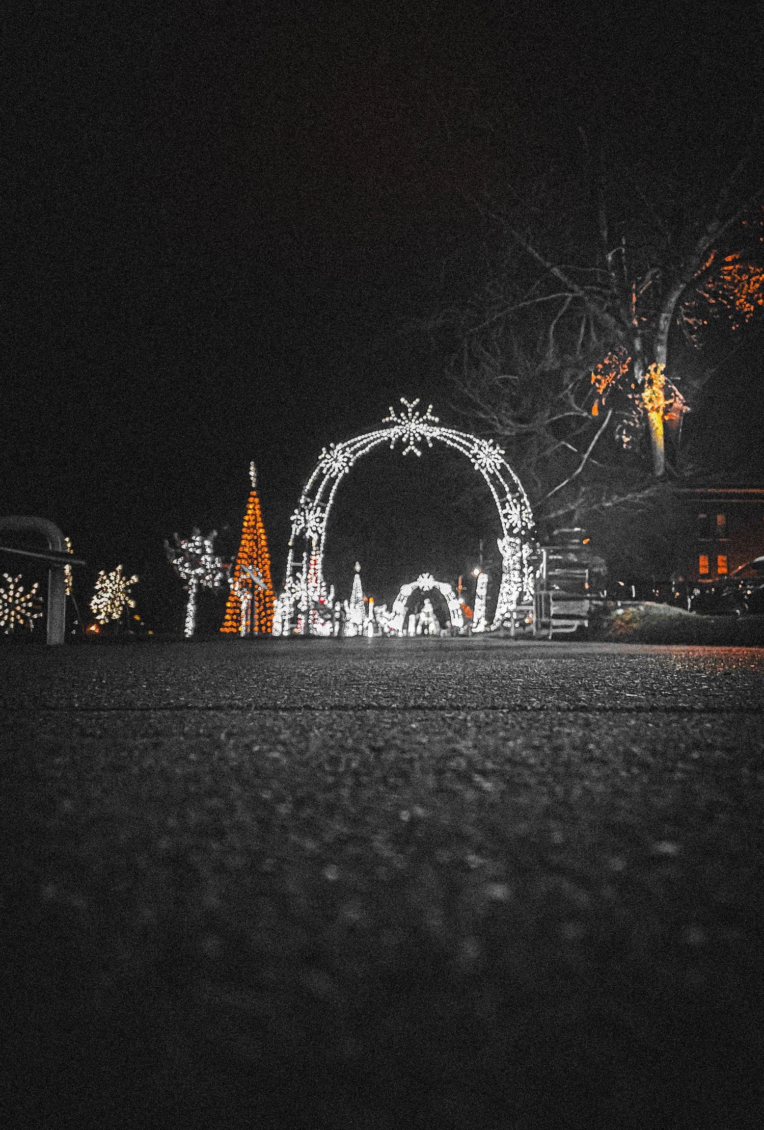 Illuminated white Christmas arch and decorations glowing against a dark night sky.