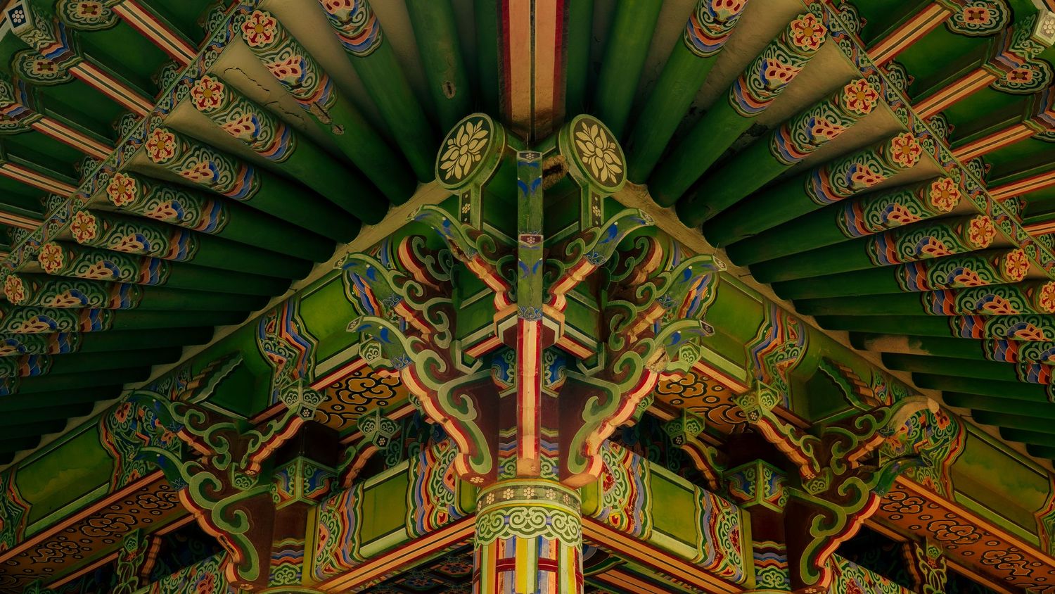Detailed view of ornate Korean temple ceiling with green and gold paintwork showing geometric patterns.
