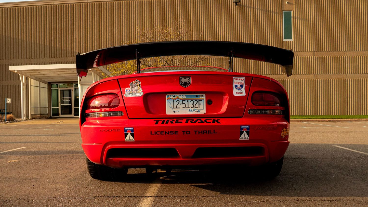 Rear view of a red Dodge Viper with large black spoiler in a parking lot.