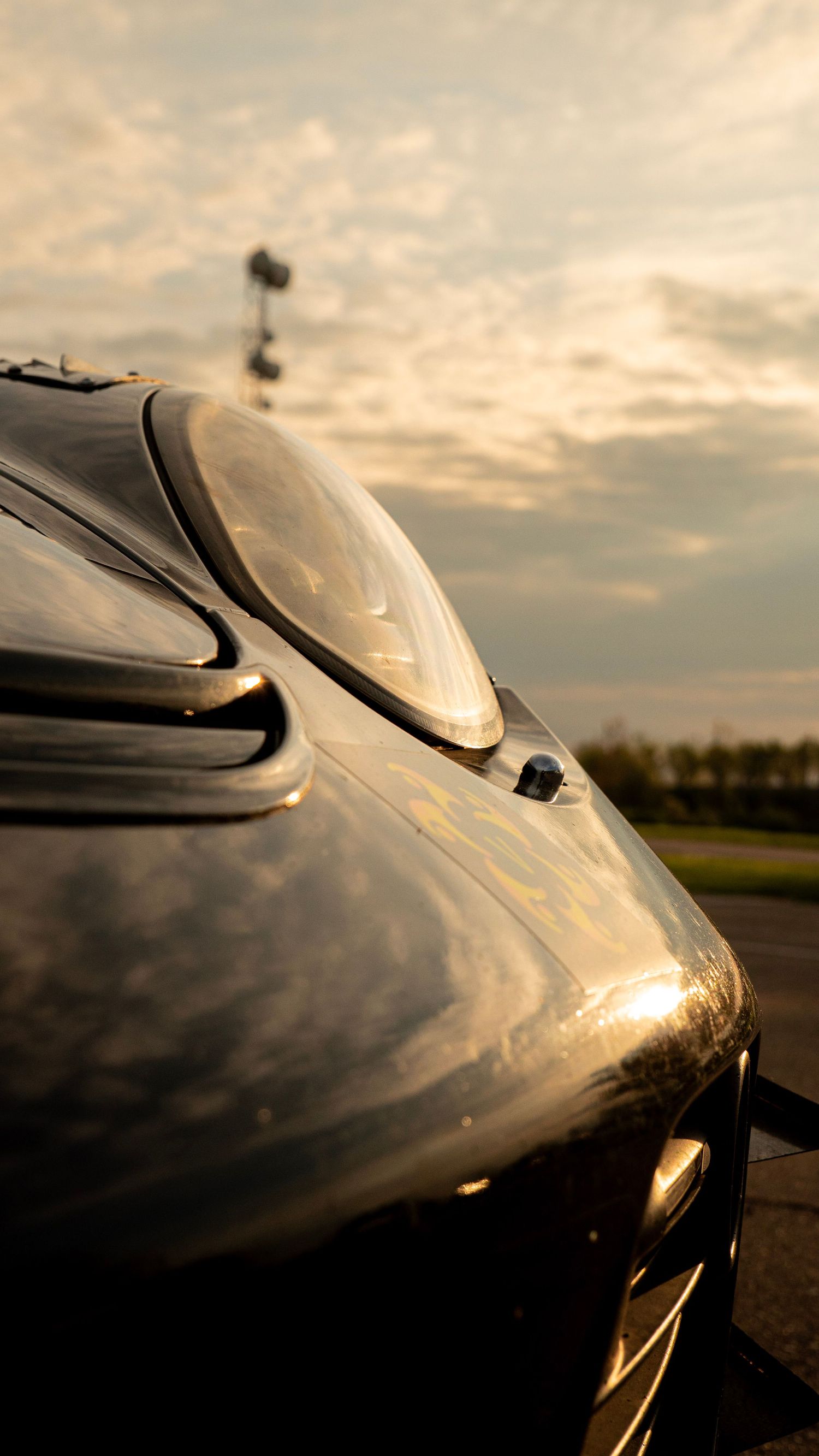 Close-up detail of black sports car headlight during golden hour.