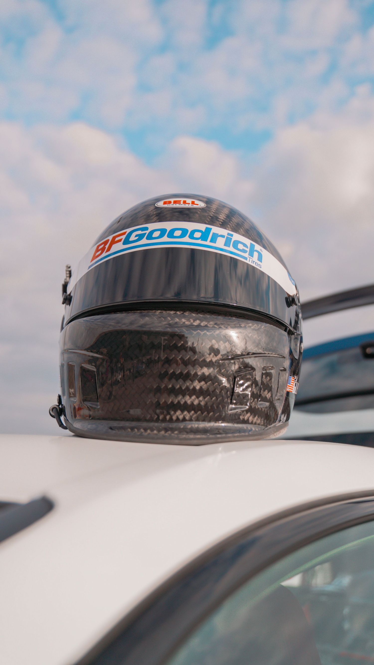 Detail shot of BFGoodrich carbon fiber racing accessory mounted on white vehicle.