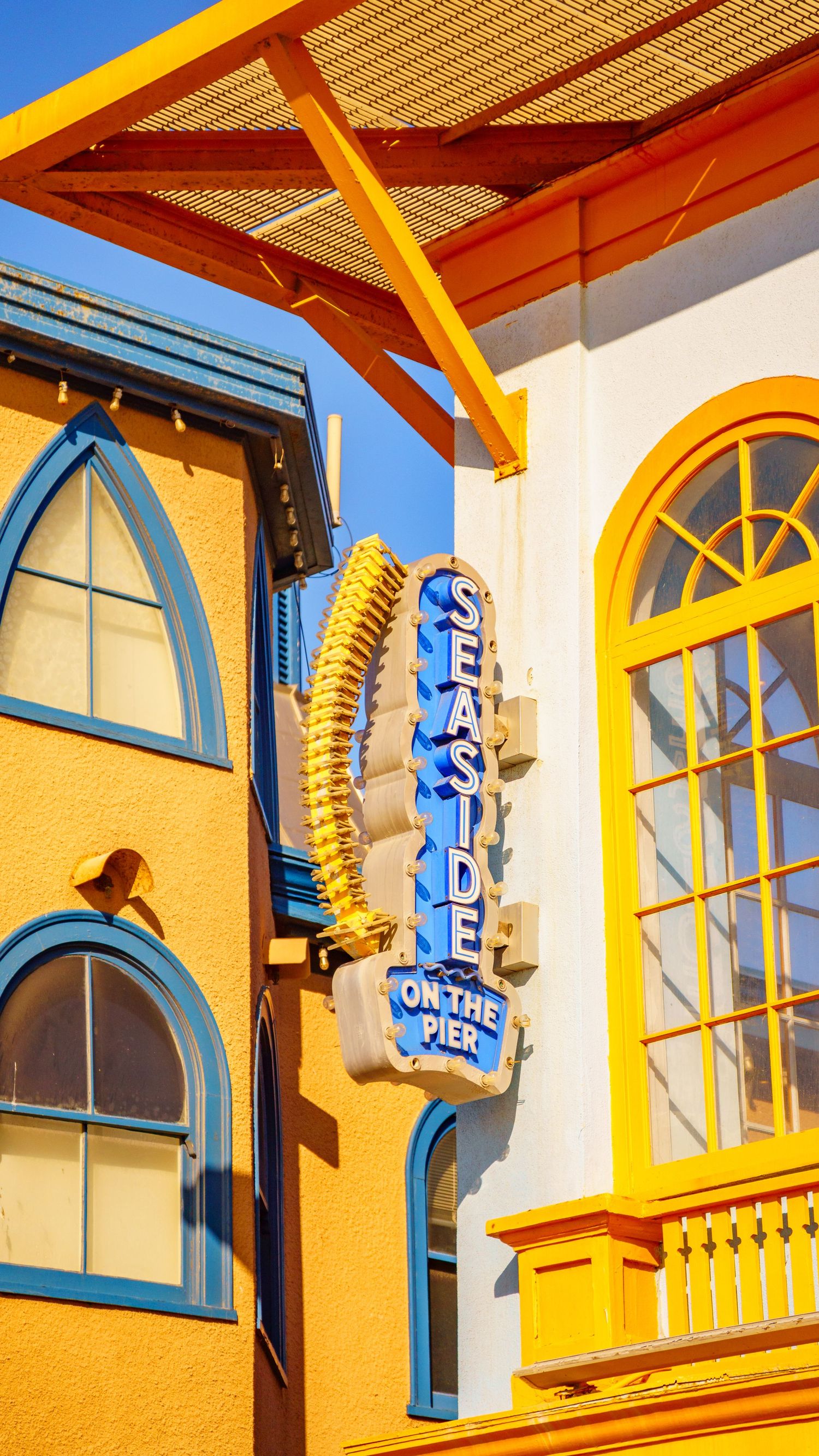 Yellow building facade with blue-trimmed arched windows and decorative signage in retro amusement park style.