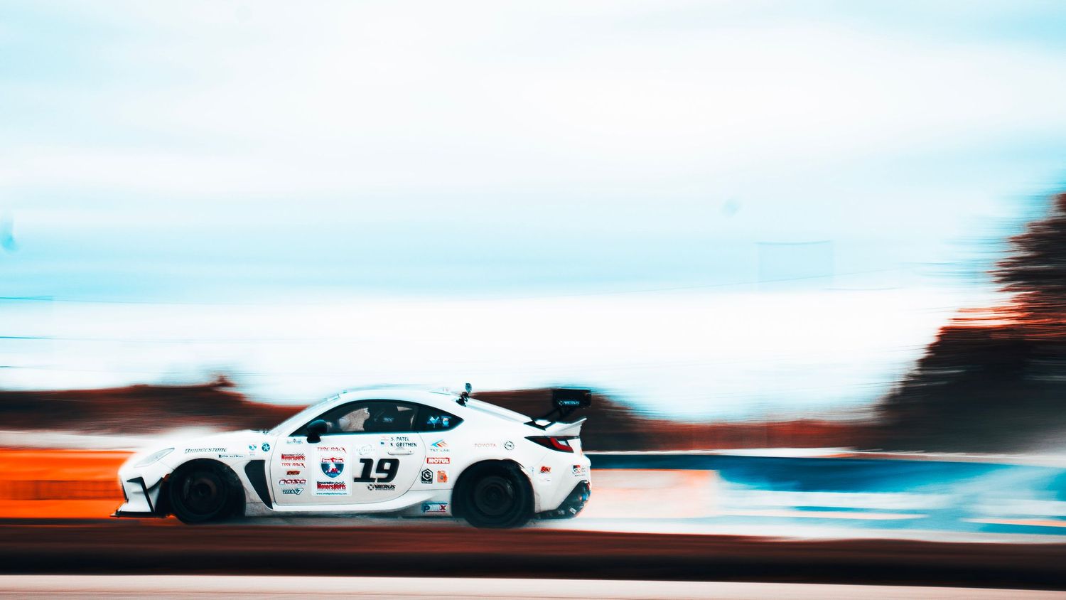White racing cars competing at high speeds on a professional race circuit.