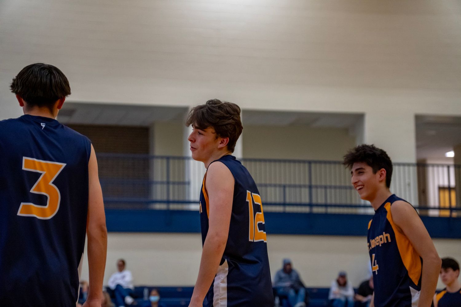 Volleyball players in numbered jerseys line up on a hardwood court during a competitive match.