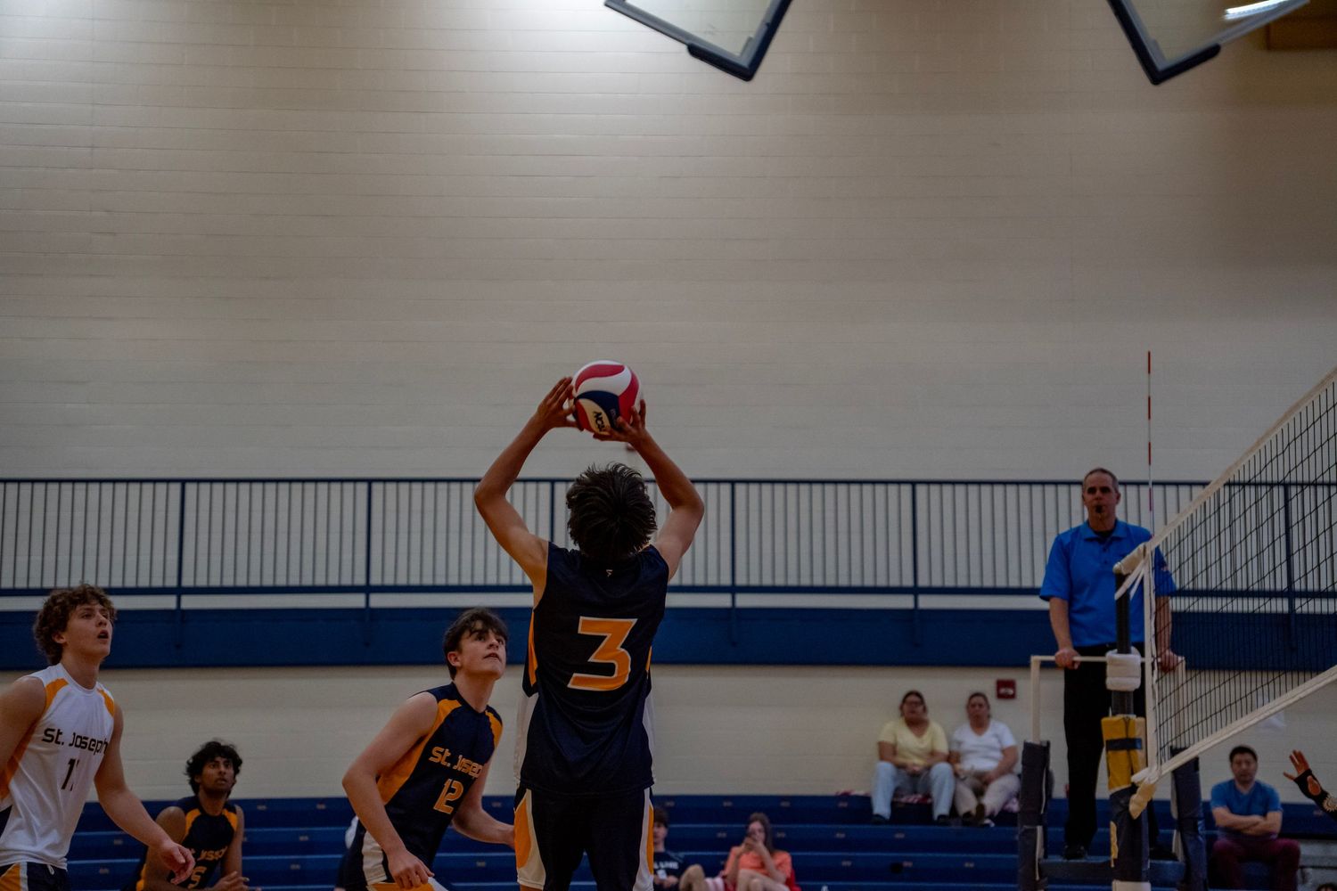 A volleyball player sets up for a shot during an indoor match.